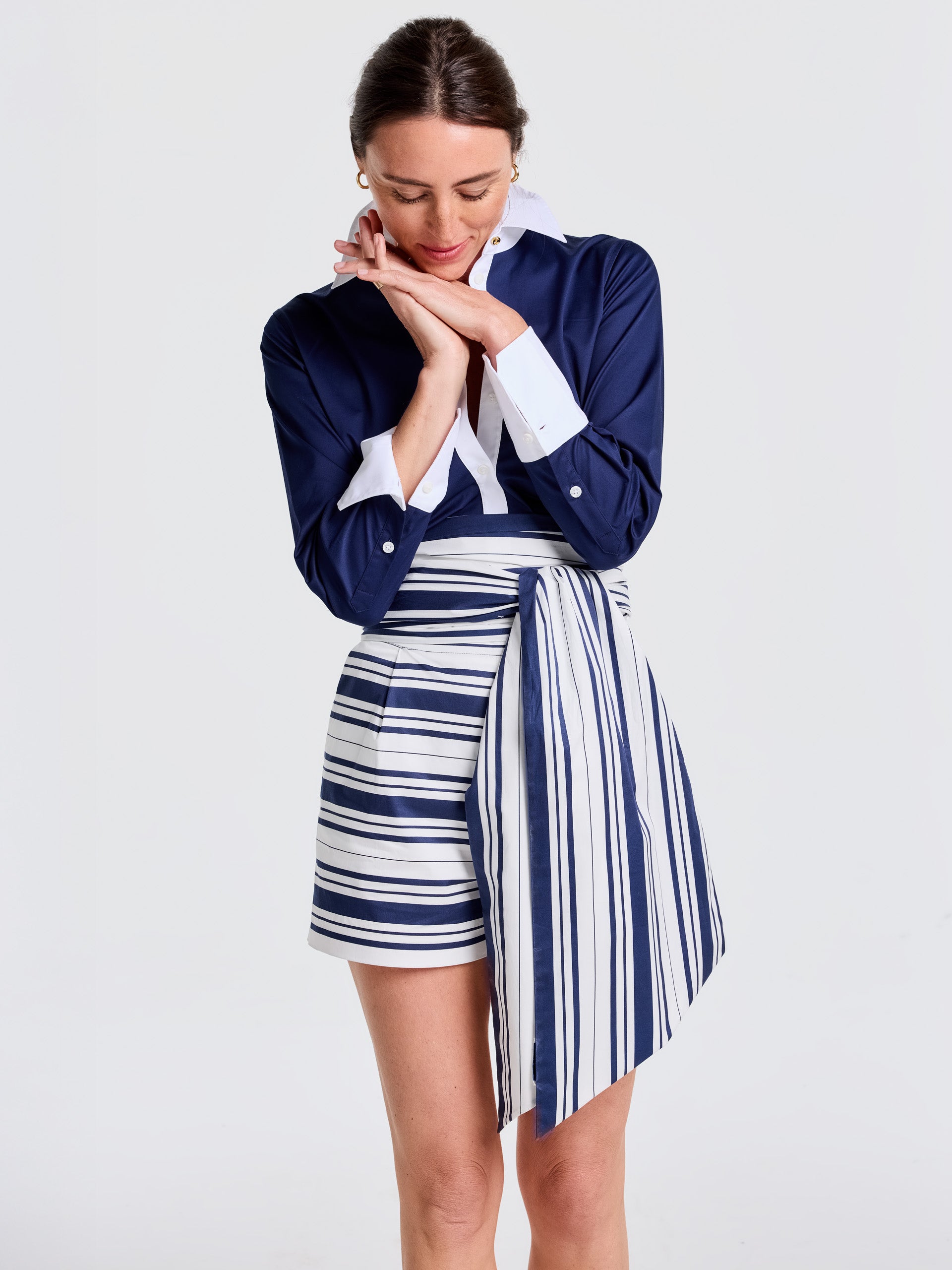 Woman wearing a navy and white striped scarf styled as a wrap around shorts, paired with a navy blouse, showcasing the Donna Scarf in Mariner Stripe by J.McLaughlin, exemplifying effortlessly stylish, enduring designs with innovative fabrics in a legacy of timeless fashion. A destination for defining style. Life, Well-Lived.