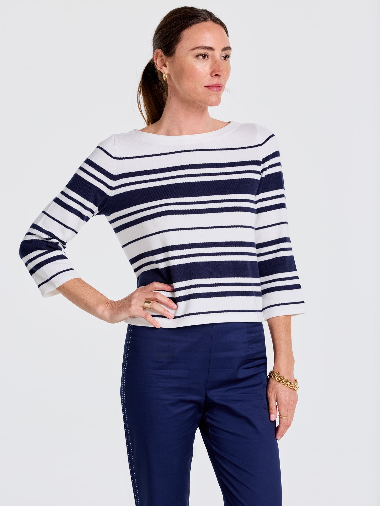 Woman wearing a J.McLaughlin Ali Sweater in Mariner Stripe with navy pants, showcasing effortlessly stylish, enduring designs and innovative fabrics for a legacy of timeless fashion.