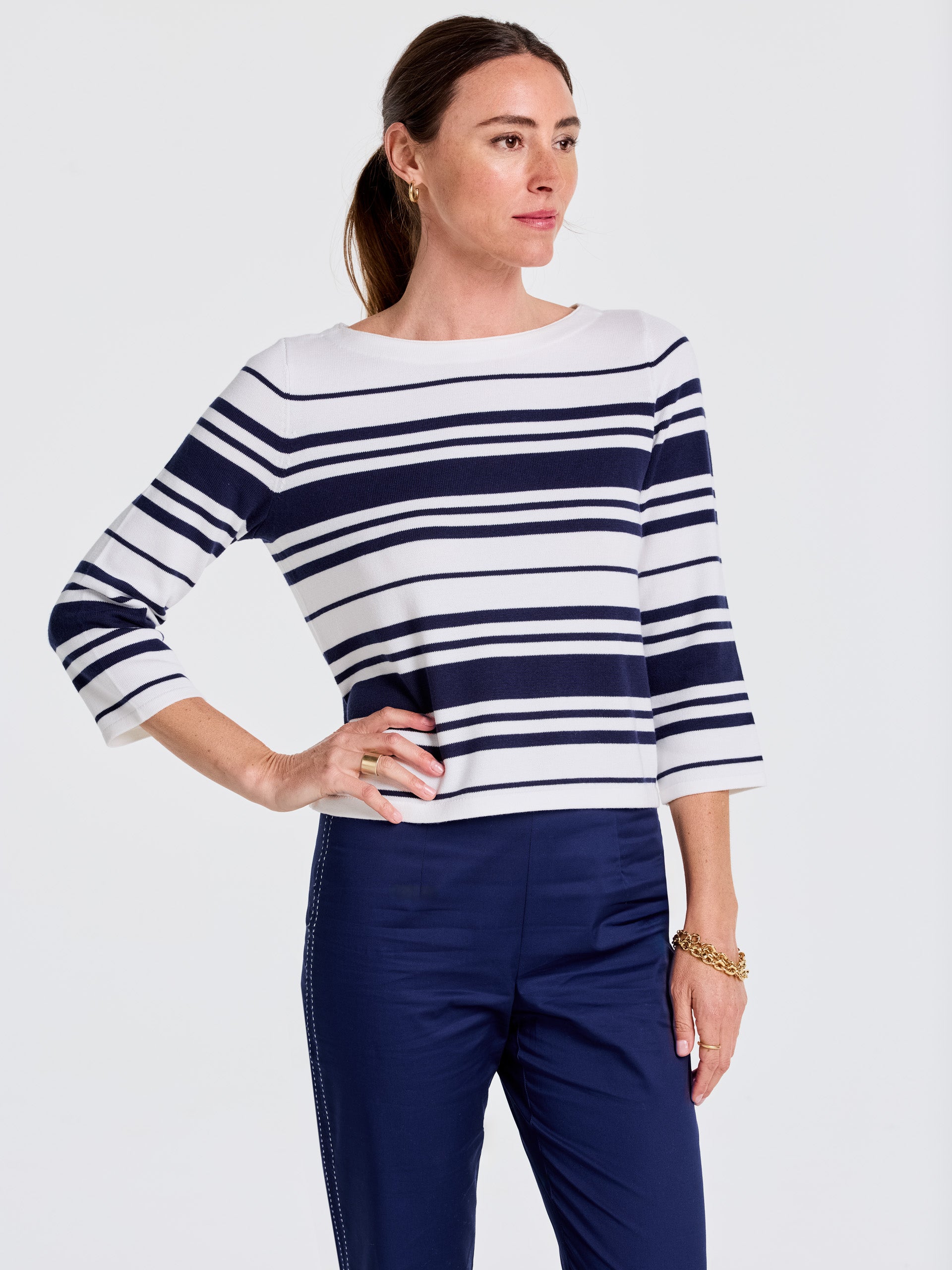 Woman wearing a J.McLaughlin Ali Sweater in Mariner Stripe with navy pants, showcasing effortlessly stylish, enduring designs and innovative fabrics for a legacy of timeless fashion.