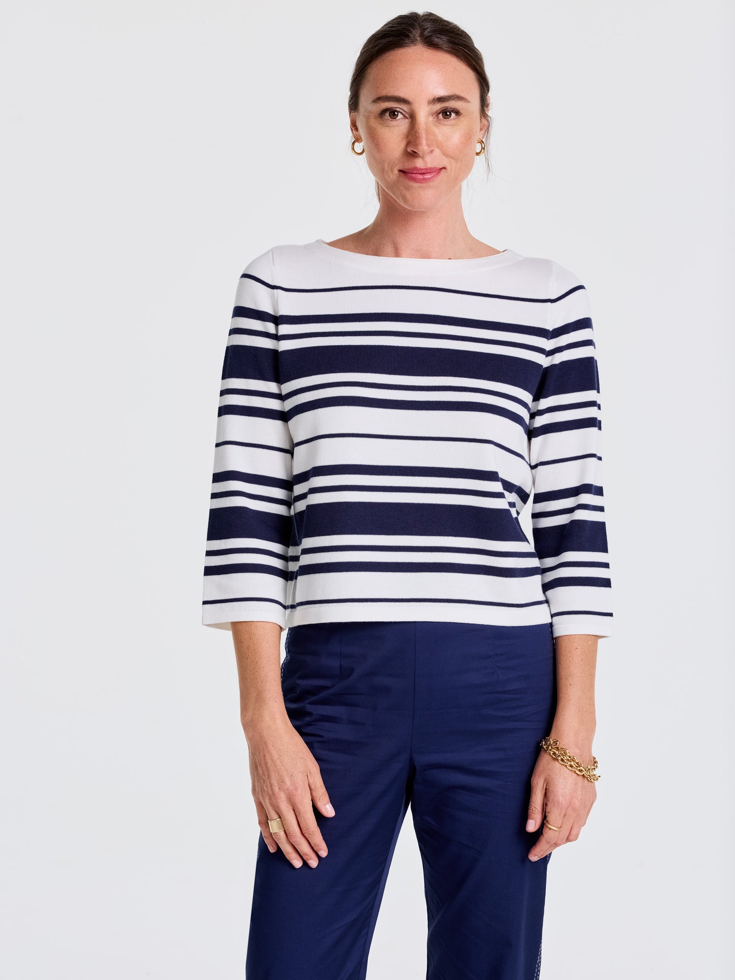 A woman wears the Ali Sweater in Mariner Stripe by J.McLaughlin, featuring effortlessly stylish navy and white stripes that embody enduring designs and innovative fabrics. A destination for defining style. Life, Well-Lived.