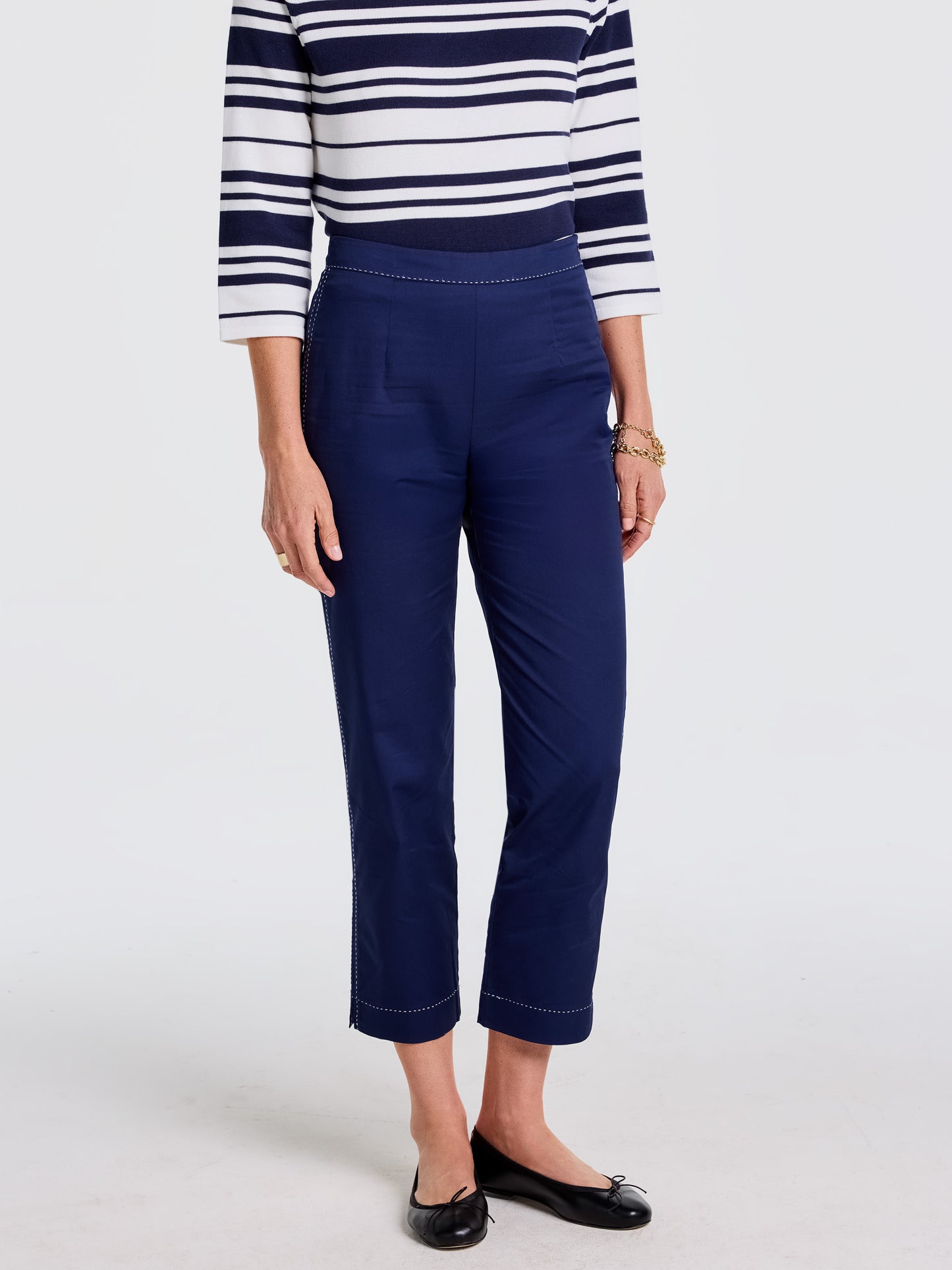 Woman wearing navy Betina Pants by J.McLaughlin paired with a striped top and black flats, showcasing effortlessly stylish, enduring designs and innovative fabrics.