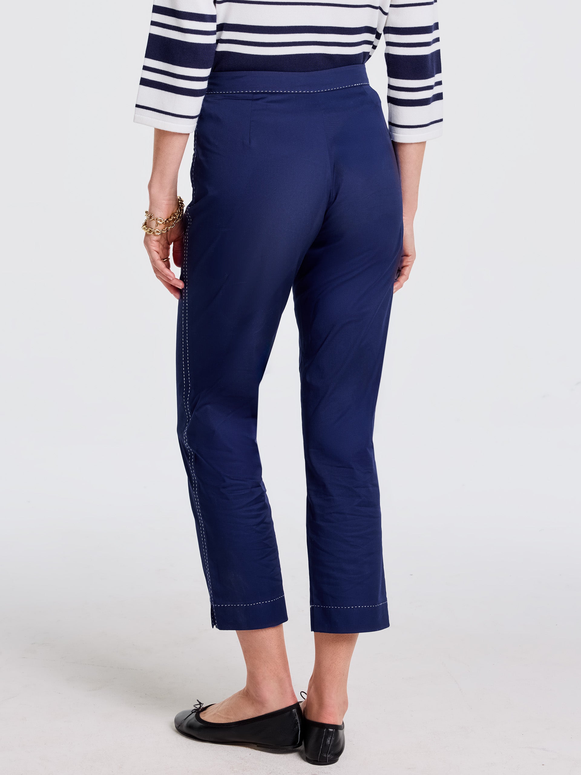 Rear view of a woman wearing navy blue Betina Pants by J.McLaughlin, paired with a striped top and black flats, showcasing effortlessly stylish pants with enduring designs and innovative fabric.