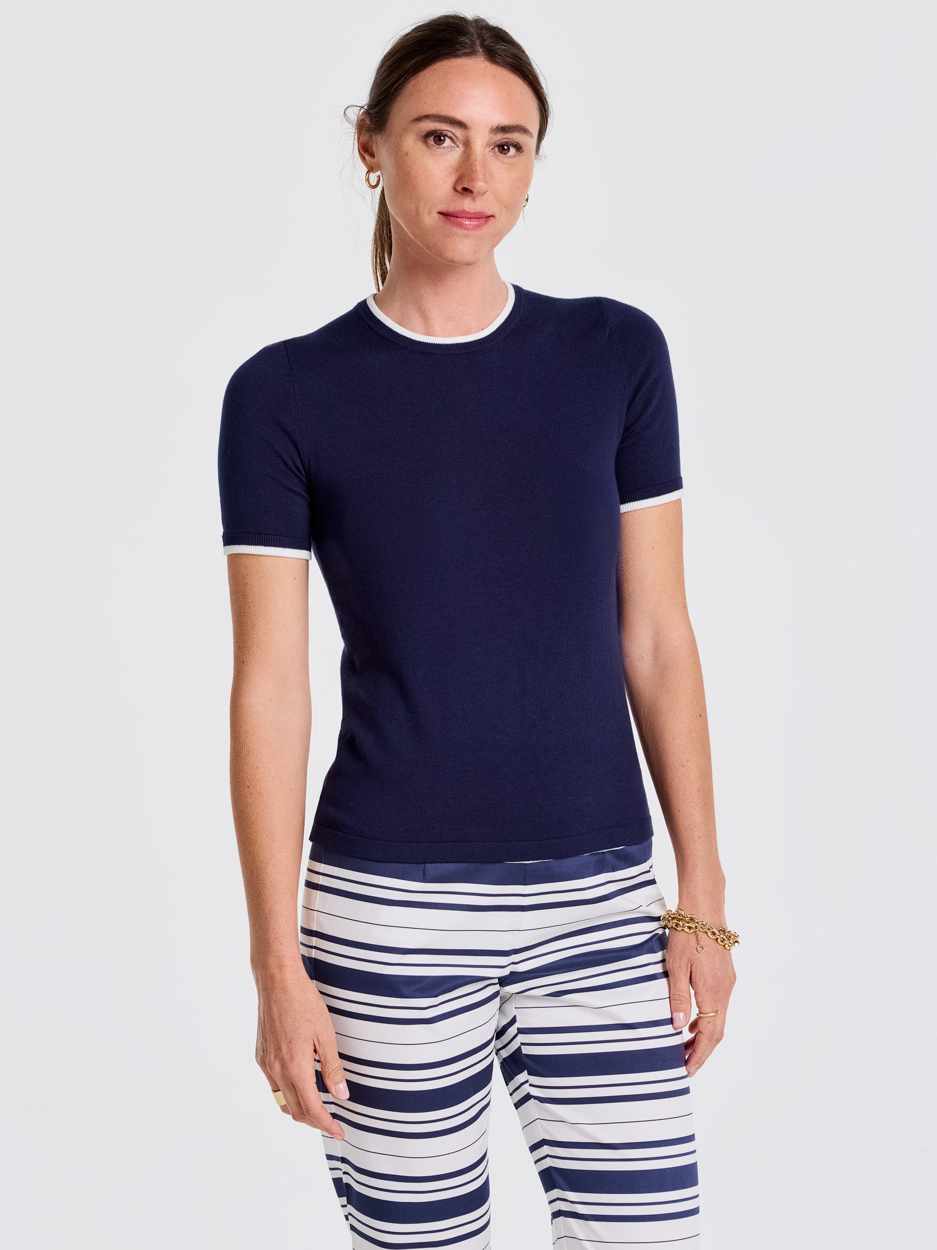 Woman wearing a navy Alyson Sweater Tee by J.McLaughlin paired with white and navy striped pants, showcasing effortlessly stylish, enduring designs and innovative fabrics for a life well-lived.