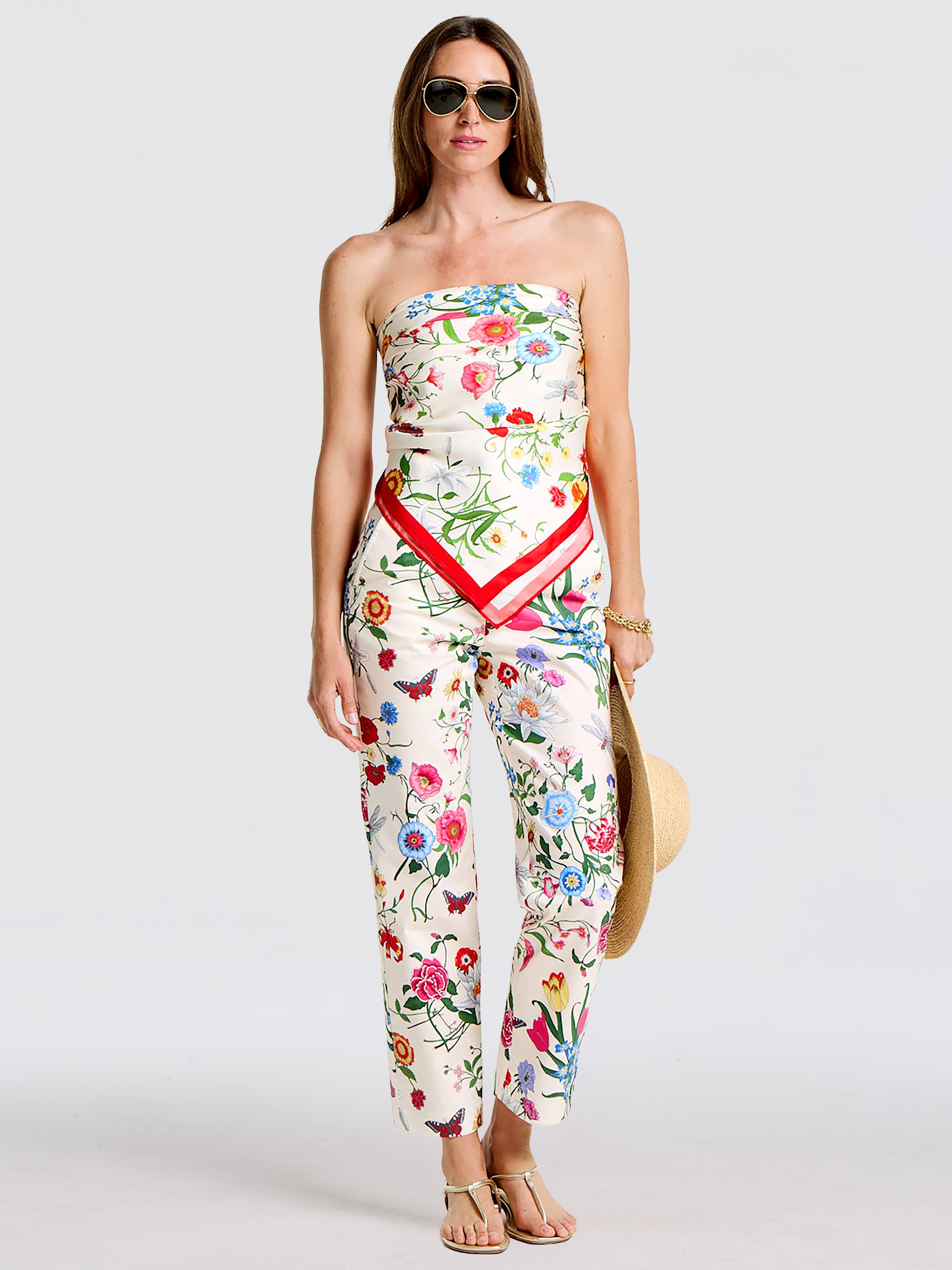 Woman wearing a floral outfit with a Kyleigh Silk Scarf in Dragonfly Garden styled as a top, paired with matching pants, sunglasses, and a hat, showcasing J.McLaughlin's effortlessly stylish, enduring designs and innovative fabrics. A destination for defining style. Life, Well-Lived.