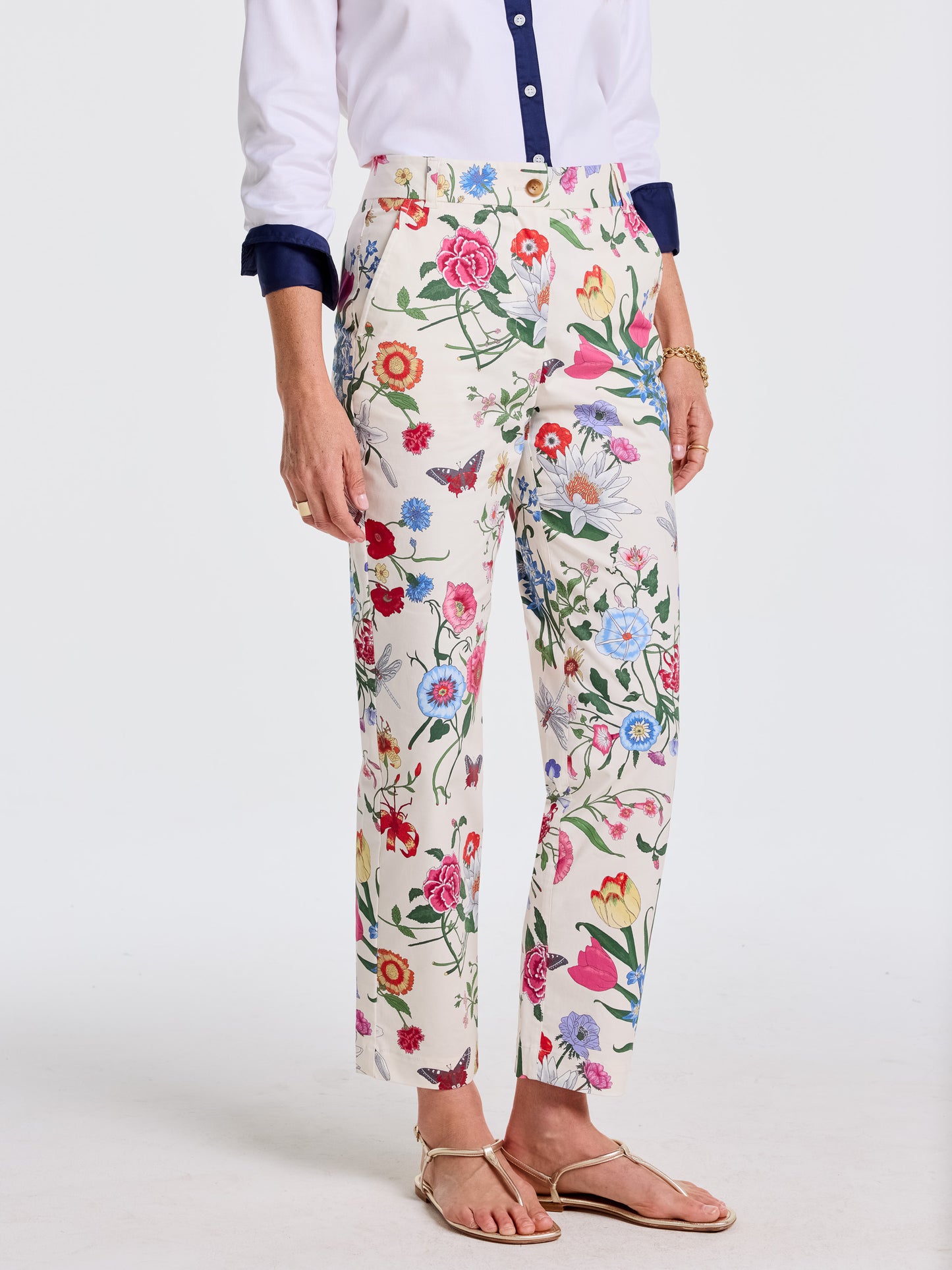 A close-up of a woman wearing Avery Pants in Dragonfly Garden by J.McLaughlin, featuring a vibrant floral pattern and paired with a white shirt with navy accents, effortlessly stylish and embodying enduring designs with innovative fabrics, a destination for defining style. Life, Well-Lived.