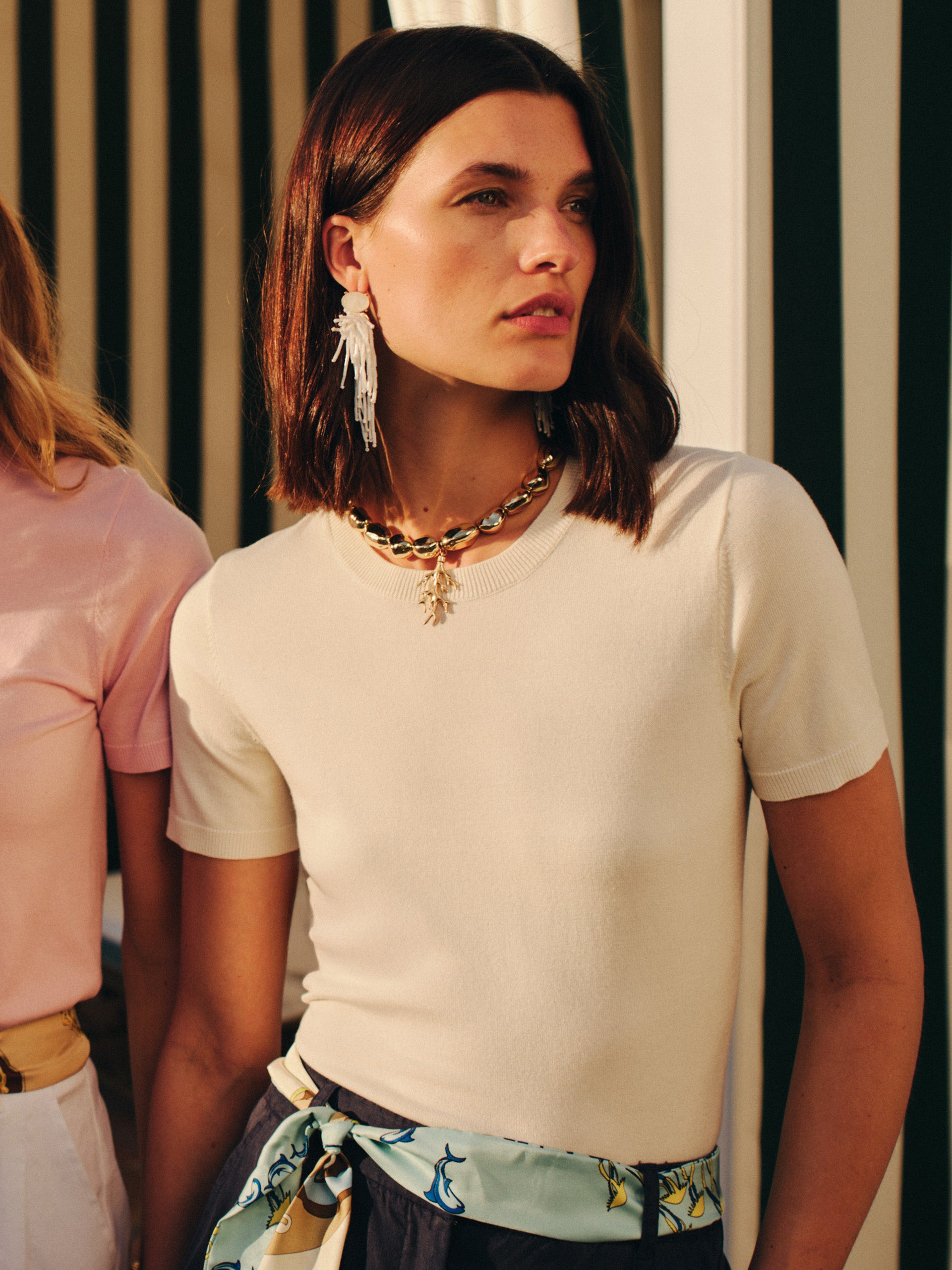 Woman wearing Beaded Tassel Earrings paired with a cream top and patterned scarf belt, showcasing J.McLaughlin's effortlessly stylish, enduring designs and legacy of timeless fashion.