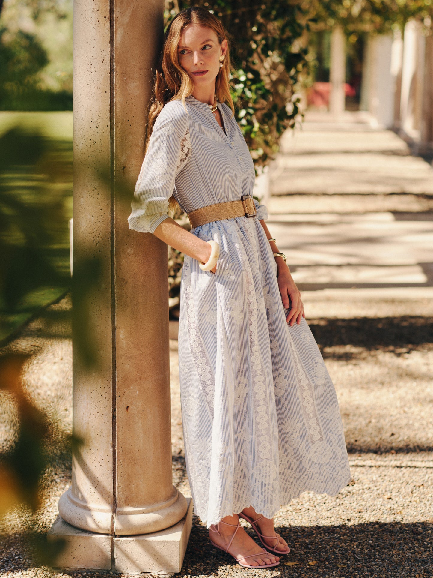 A woman models the Margaret Dress in Stripe by J.McLaughlin, featuring a belted waist and delicate stripes with subtle floral patterns, embodying effortlessly stylish, enduring designs and innovative fabrics. A destination for defining style. Life, Well-Lived.