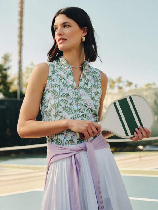 Woman wearing a Kate Sleeveless Ruffle Top in Neo Blooming Vines by J.McLaughlin, styled with a lilac sweater tied at the waist, embodying effortlessly stylish, enduring designs.