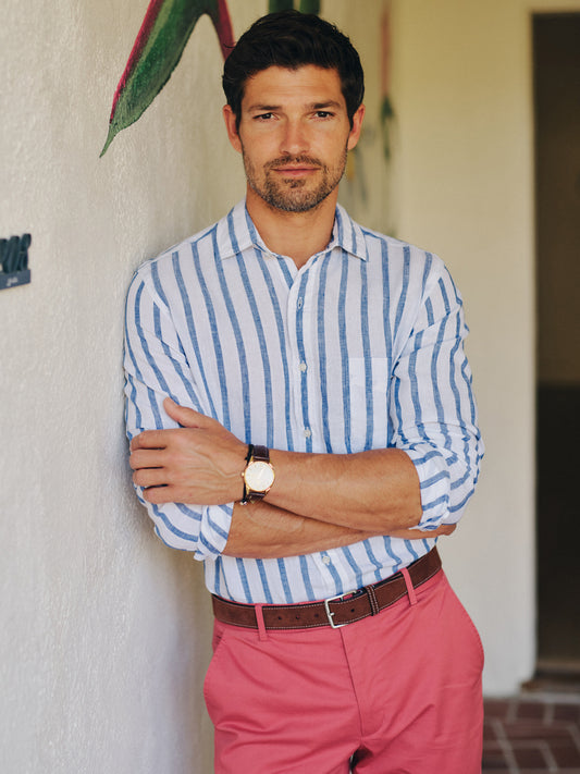 Man wearing a Gramercy Linen Shirt in Dobby Stripe by J.McLaughlin with rolled sleeves and pink pants, embodying effortlessly stylish, enduring designs and innovative fabrics.