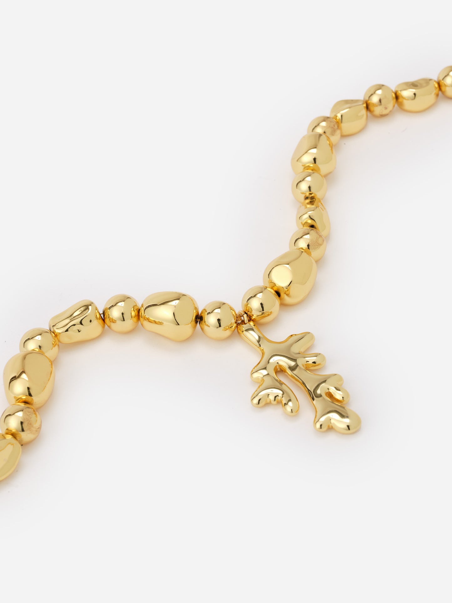 Close-up of a gold-tone Coral Necklace by J.McLaughlin featuring polished, irregularly shaped beads and a coral-inspired pendant, embodying effortlessly stylish, enduring design.