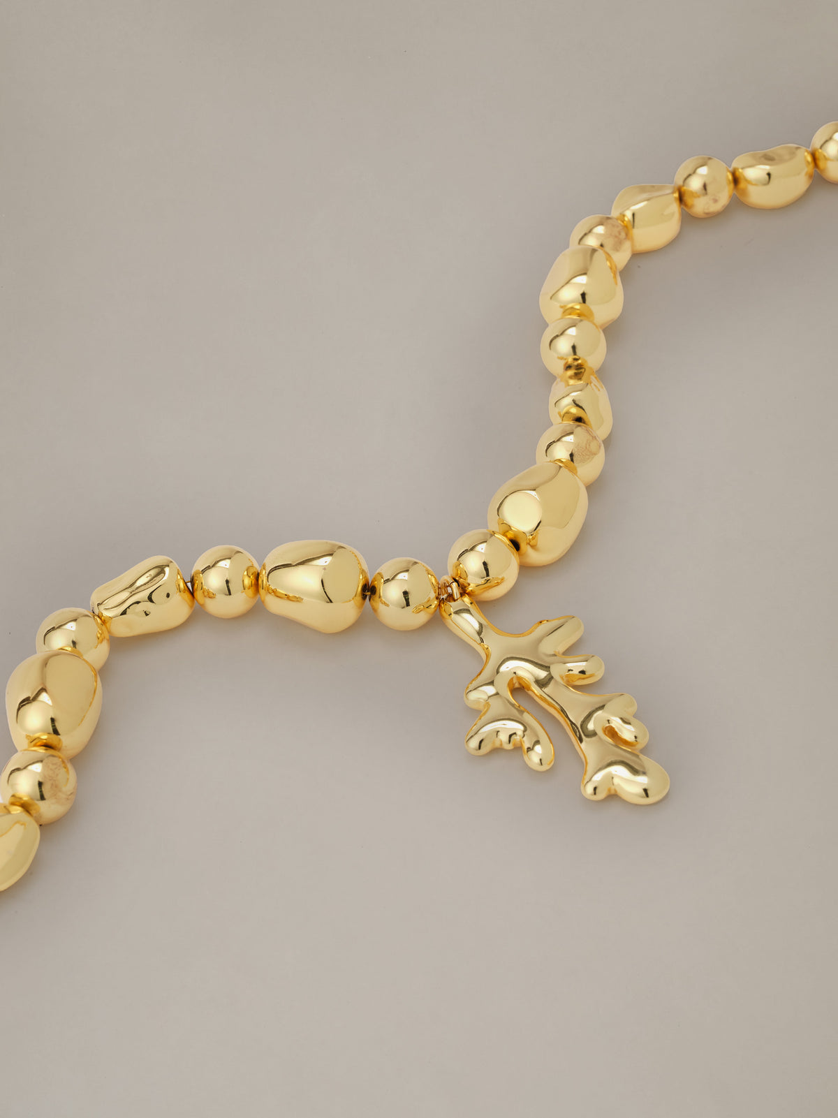 Coral Necklace by J.McLaughlin featuring a gold plated coral inspired pendant and organic textured beads on a refined chain against a neutral background.