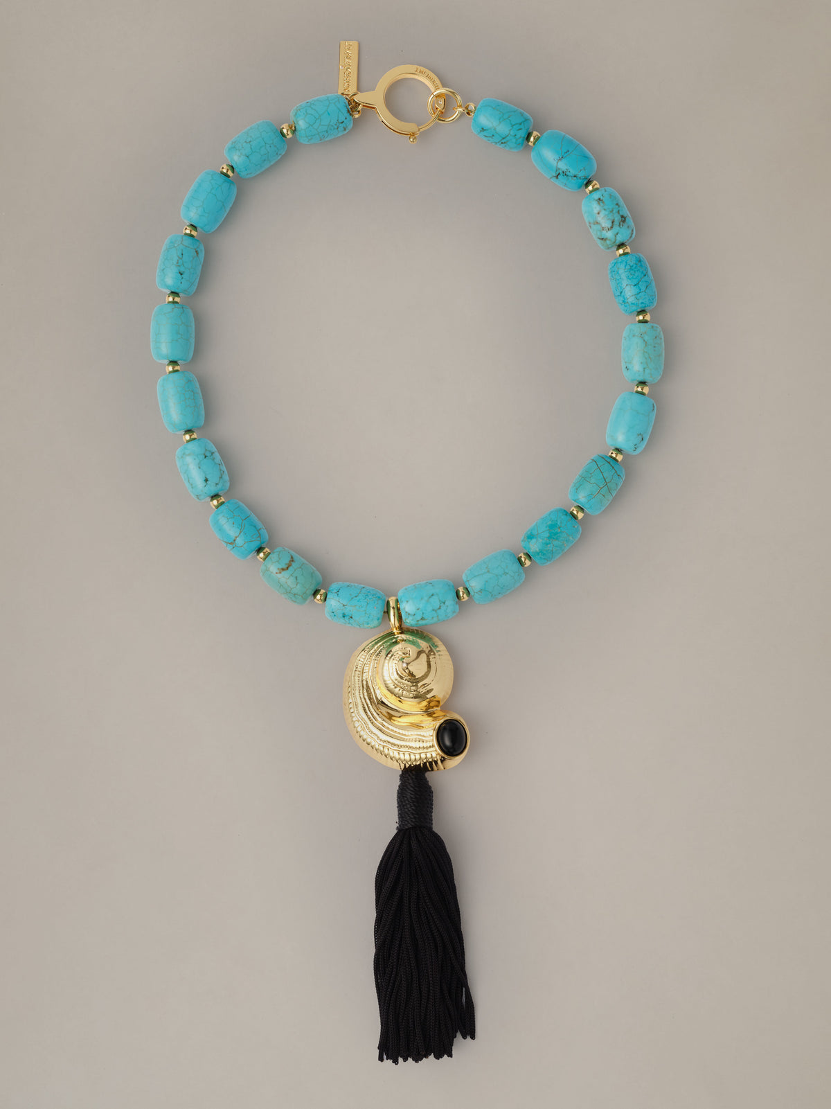 Shell Tassel Necklace by J.McLaughlin with turquoise beads and a gold shell pendant finished with a long black tassel for coastal style