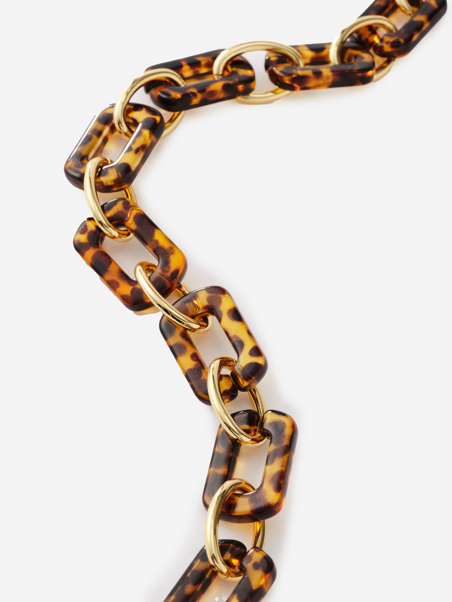 Close-up of a Chain Link Necklace featuring tortoiseshell-patterned resin links connected by polished gold rings, showcasing J.McLaughlin’s legacy of timeless fashion and enduring designs.