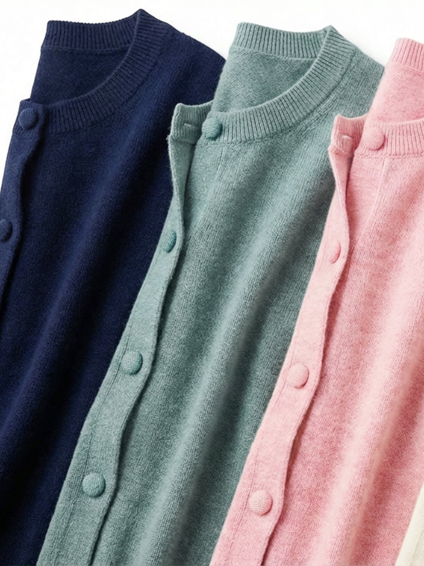 Three Pearl Cardigans from J.McLaughlin in navy, soft green, and blush pink featuring fabric-covered buttons, showcasing effortlessly stylish knitwear with enduring designs and innovative fabrics.