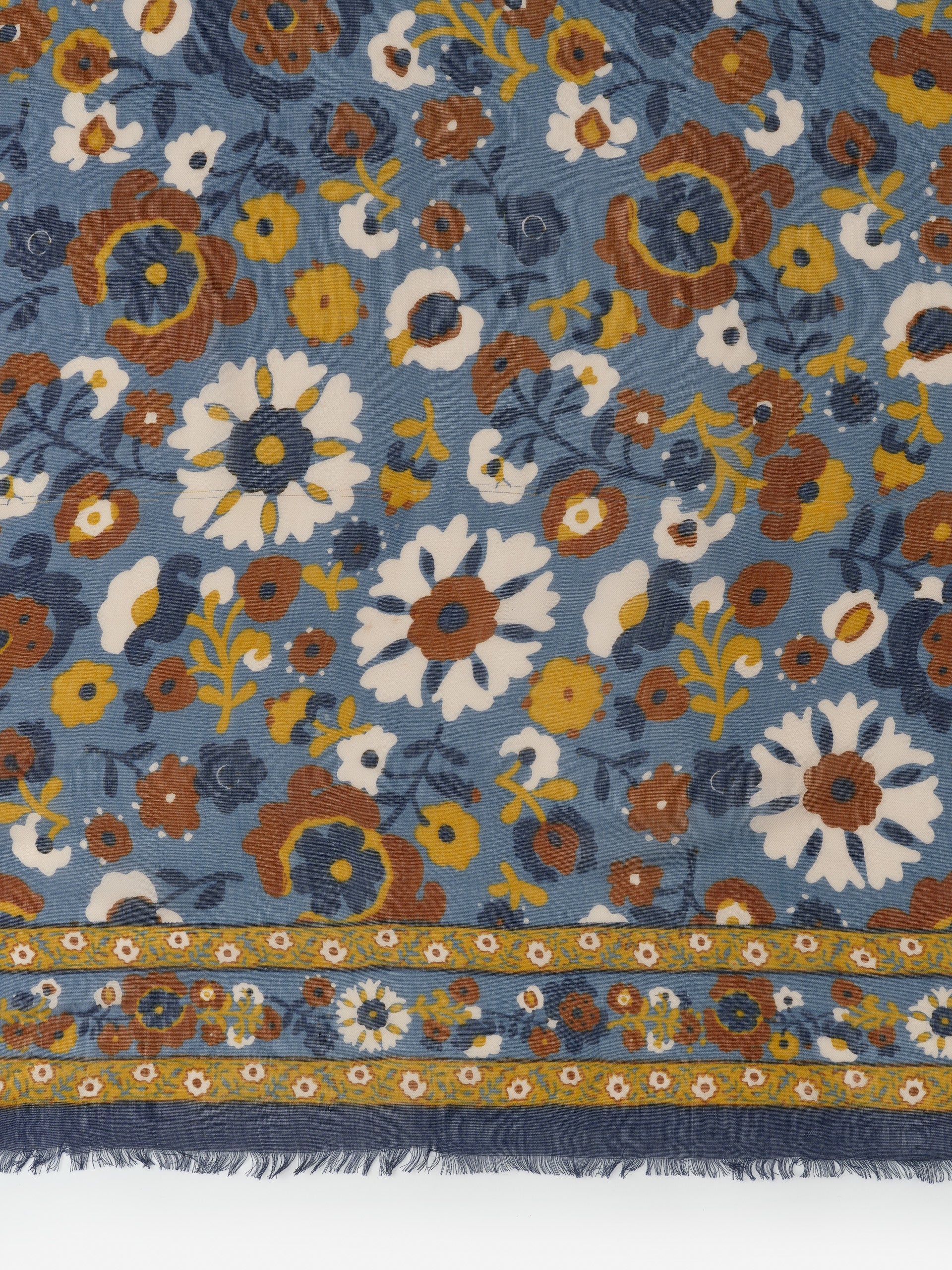 Close-up of the Giselle Scarf in Floral Daydream Border by J.McLaughlin featuring a blue background with vintage-inspired floral patterns in white, mustard, and brown, showcasing effortlessly stylish, enduring designs and innovative fabrics from a destination for defining style. Life, Well-Lived.