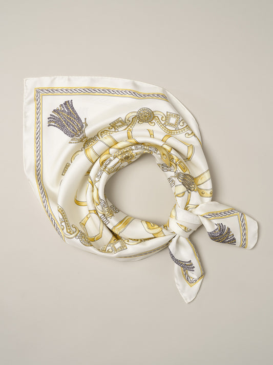 The Grace Silk Scarf in Heraldic Tassel Square by J.McLaughlin in ivory silk with a gold heraldic pattern and tassel details styled as a neck scarf