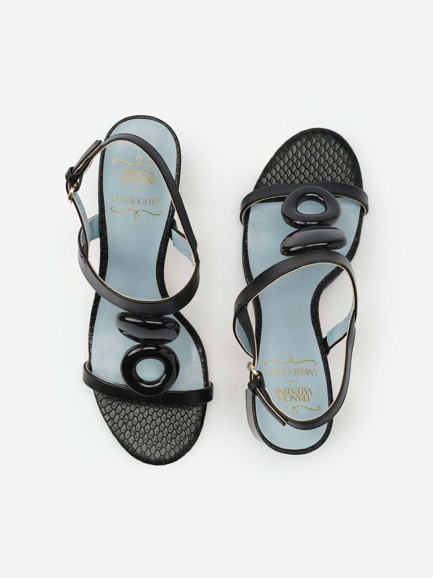 Bianca Heels by J.McLaughlin feature effortlessly stylish black leather sandals with unique glossy oval embellishments, showcasing enduring designs and a legacy of timeless fashion.