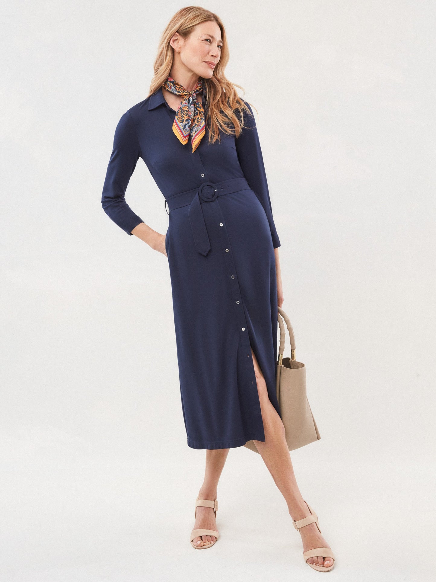 Model wears J.McLaughlin Pamela dress in deep navy made with rayon/nylon/spandex.
