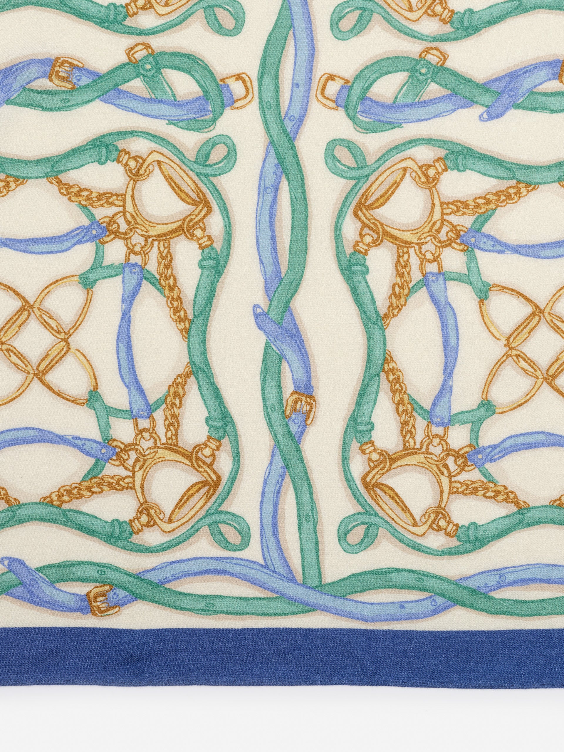 Close-up of J.McLaughlin’s Sarita Scarf in Riding Lessons Corner featuring a delicate pattern of intertwined leather straps and chains in soft blue and green tones on cream, embodying effortlessly stylish, enduring designs with a legacy of timeless fashion at a destination for defining style. Life, Well-Lived.
