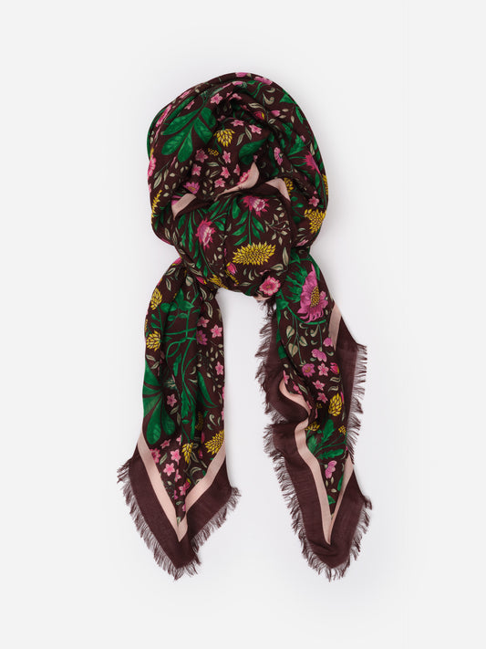 The Katherine Scarf in Mega Manor Floral Border by J.McLaughlin featuring a rich floral pattern in green, pink, and yellow on a dark background with a soft, fringed edge.