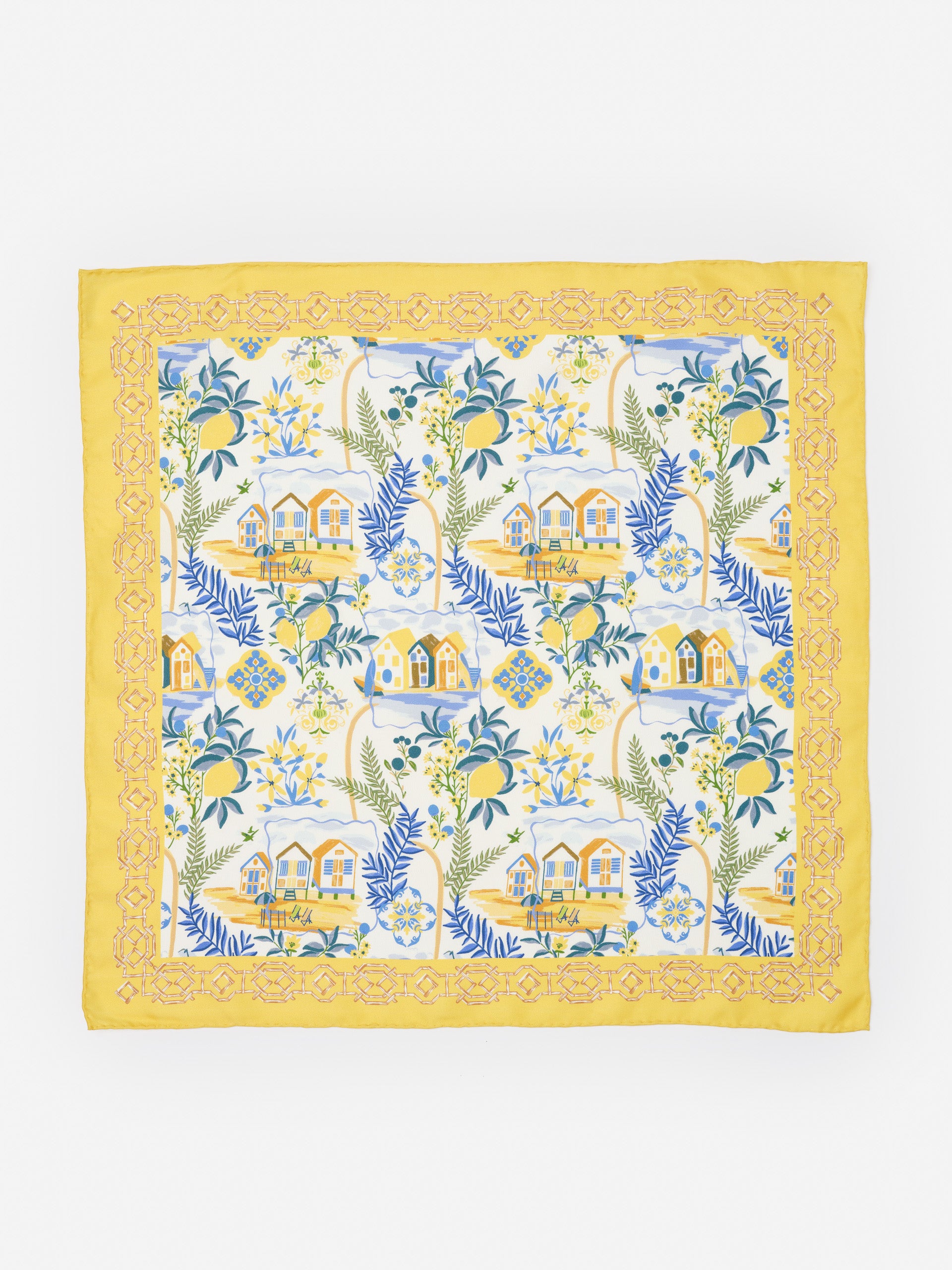 Nikka Silk Scarf in Amalfi Coast Bamboo by J.McLaughlin features a yellow border with intricate patterns framing a coastal scene of houses, lemons, and leafy branches, showcasing effortlessly stylish design and innovative fabrics in an enduring accessory. A destination for defining style. Life, Well-Lived.