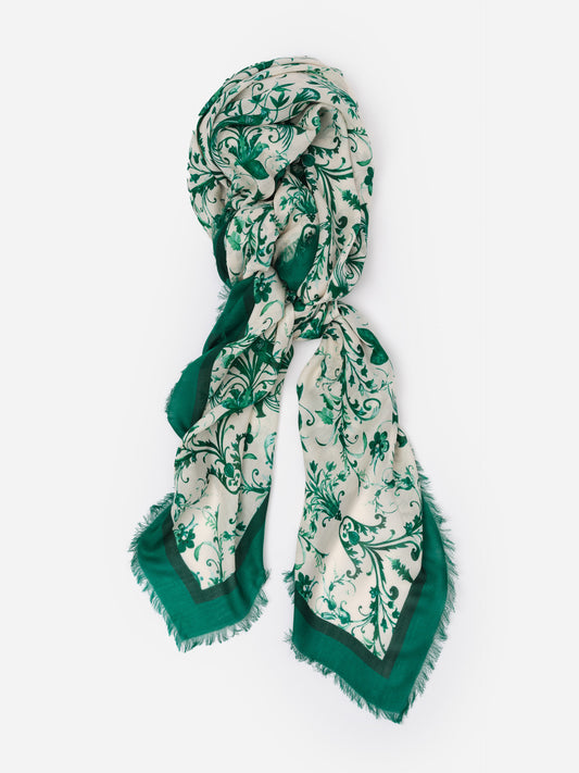 The Katherine Scarf in Garden Flight Border by J.McLaughlin, a soft modal-wool blend scarf with green floral patterns and a classic border, perfect for year-round style.