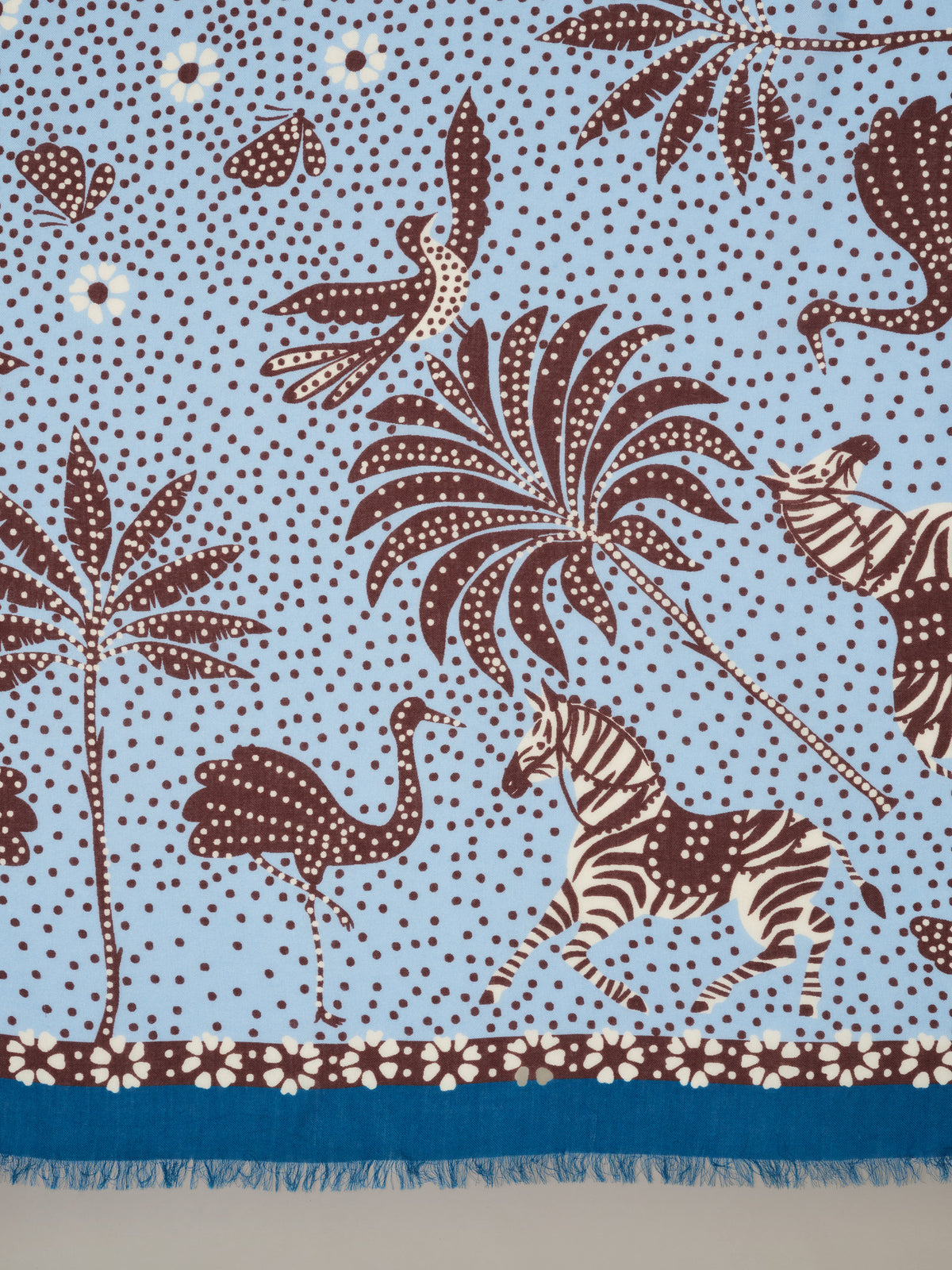 The Katherine Scarf in Folk Tale Border by J.McLaughlin featuring a blue modal wool scarf with brown botanical motifs birds zebra and fringed floral border
