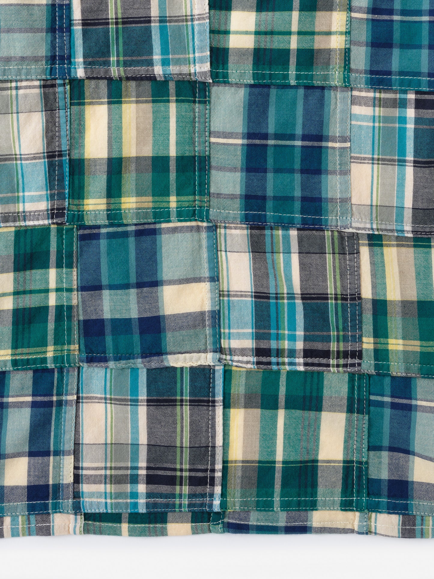 Close-up of a patchwork design featuring various shades of blue, green, cream, and yellow in the Men's Cotton Scarf in Plaid by J.McLaughlin, showcasing innovative fabrics and enduring designs from a destination for defining style. Life, Well-Lived.