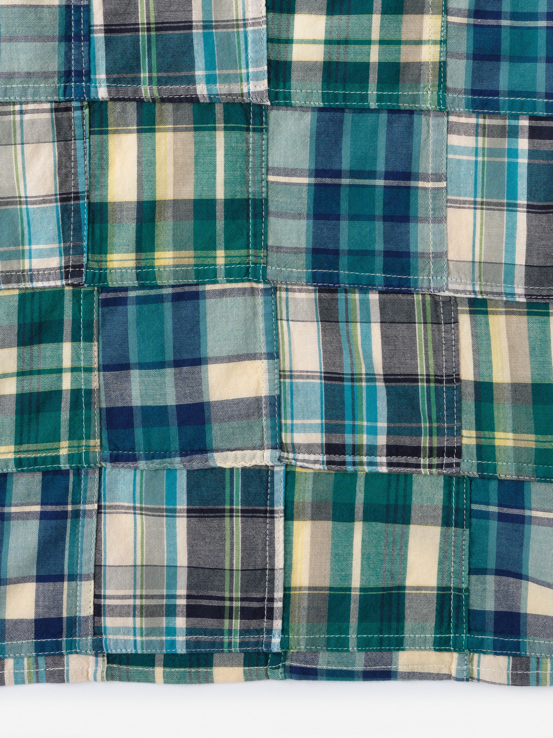 Close-up of a patchwork design featuring various shades of blue, green, cream, and yellow in the Men's Cotton Scarf in Plaid by J.McLaughlin, showcasing innovative fabrics and enduring designs from a destination for defining style. Life, Well-Lived.