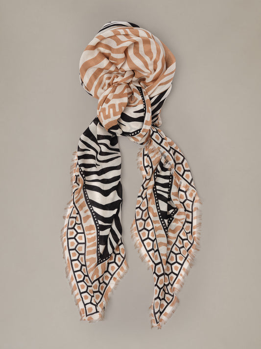 The Katherine Scarf in Wild Medley Border by J.McLaughlin in tan black and cream with geometric and zebra inspired patterns and fringed ends styled around the head and neck