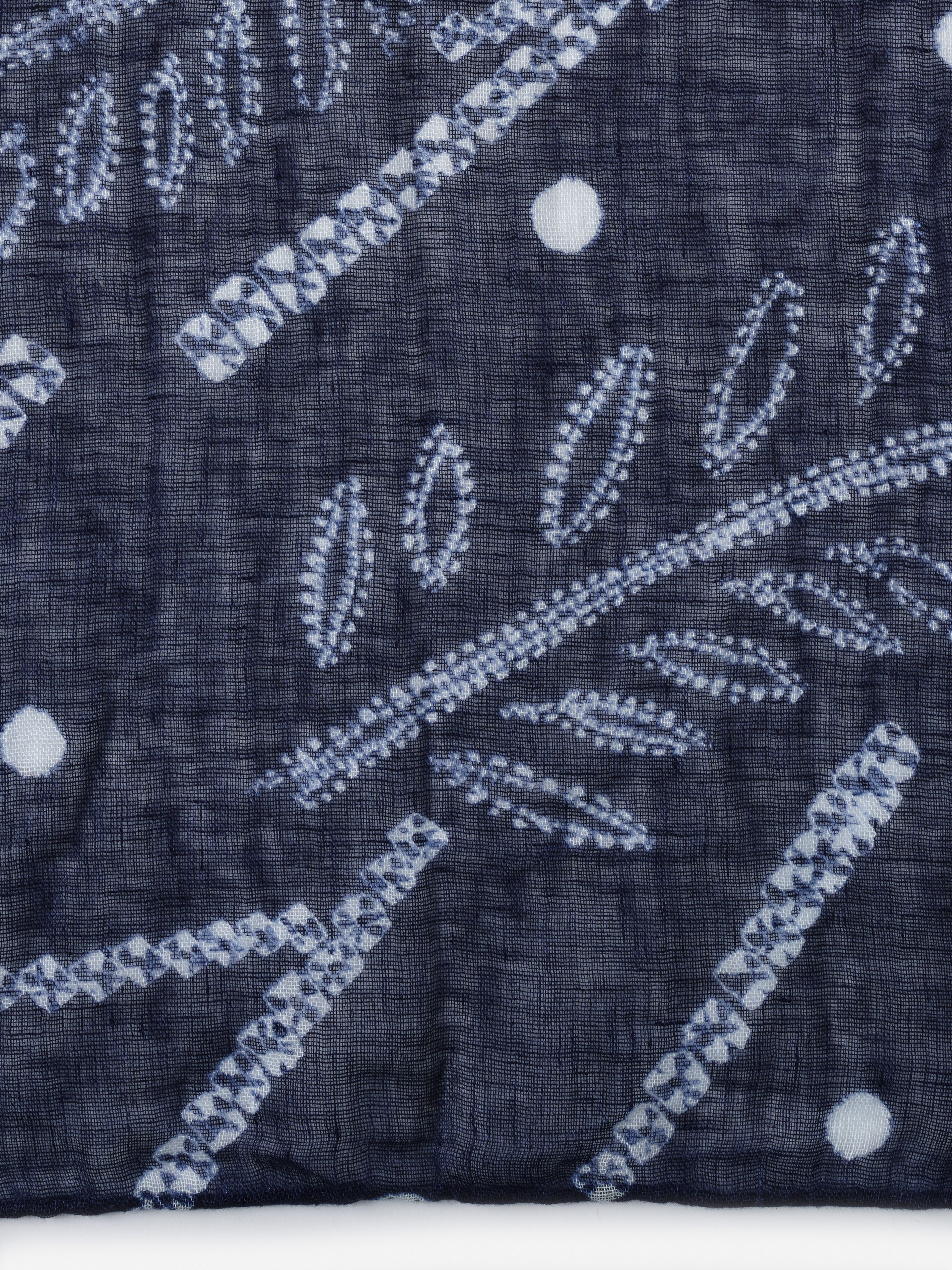 Close-up of the blue fabric with white leaf and dot patterns from the Men's Linen Scarf in Shibori Leaves by J.McLaughlin, showcasing effortlessly stylish, enduring designs and innovative fabrics.