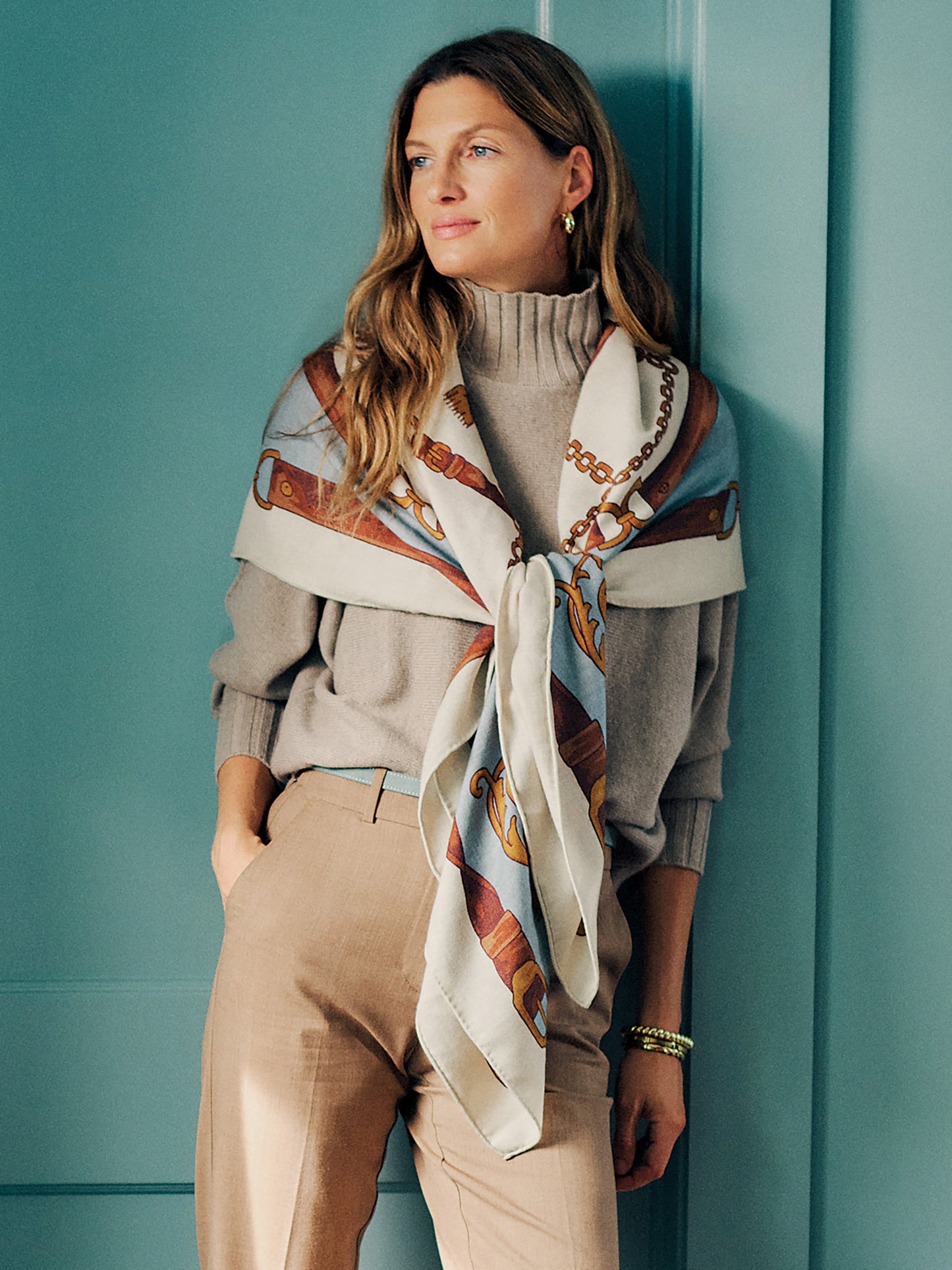 The Charlotte Scarf in Gilded Bridle Border by J.McLaughlin styled on a woman with a soft patterned scarf draped over a neutral sweater