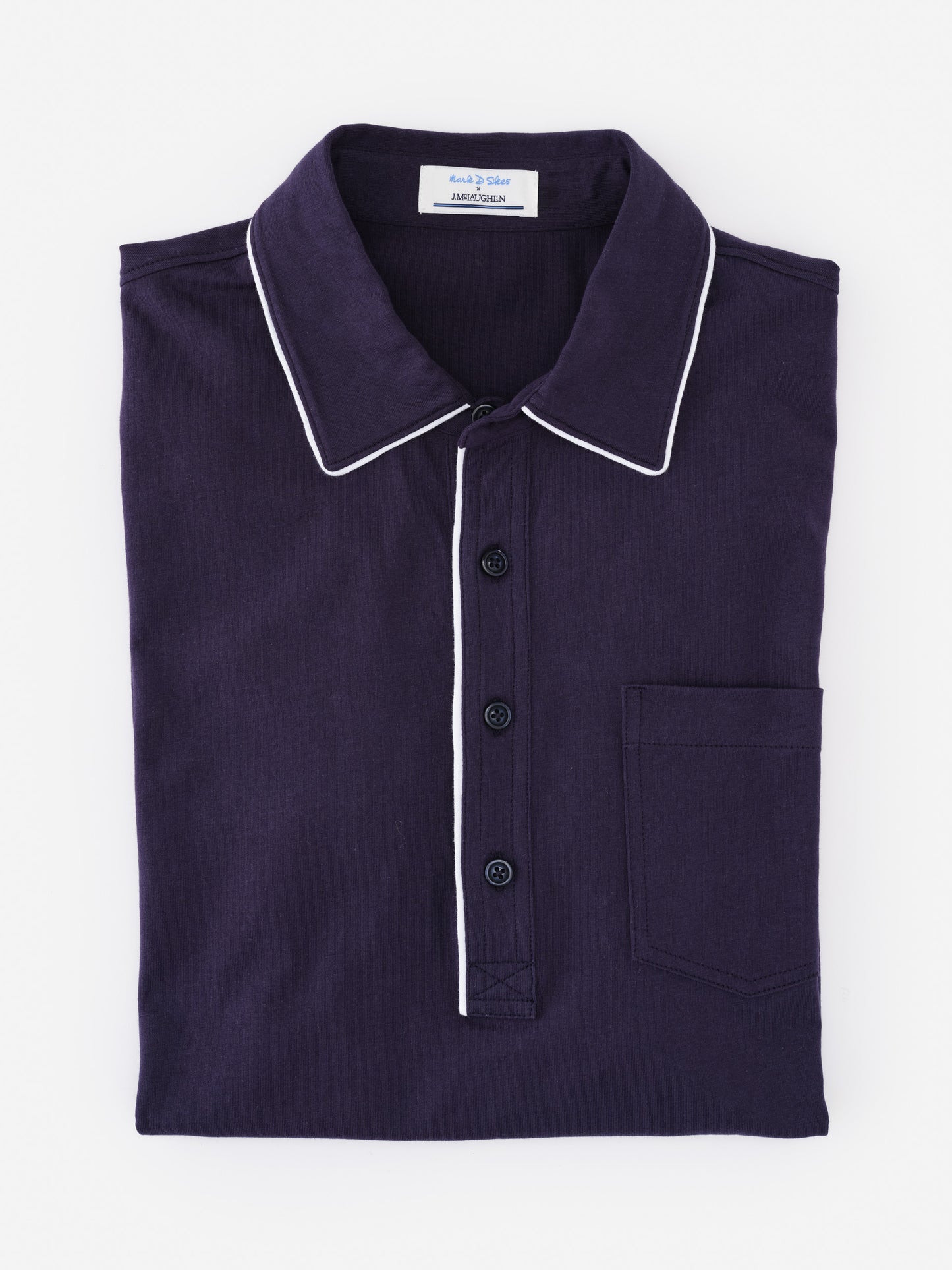 Folded navy blue Ryan Polo shirt by J.McLaughlin featuring white trim on the collar and button placket, showcasing effortlessly stylish, enduring designs and innovative fabrics.