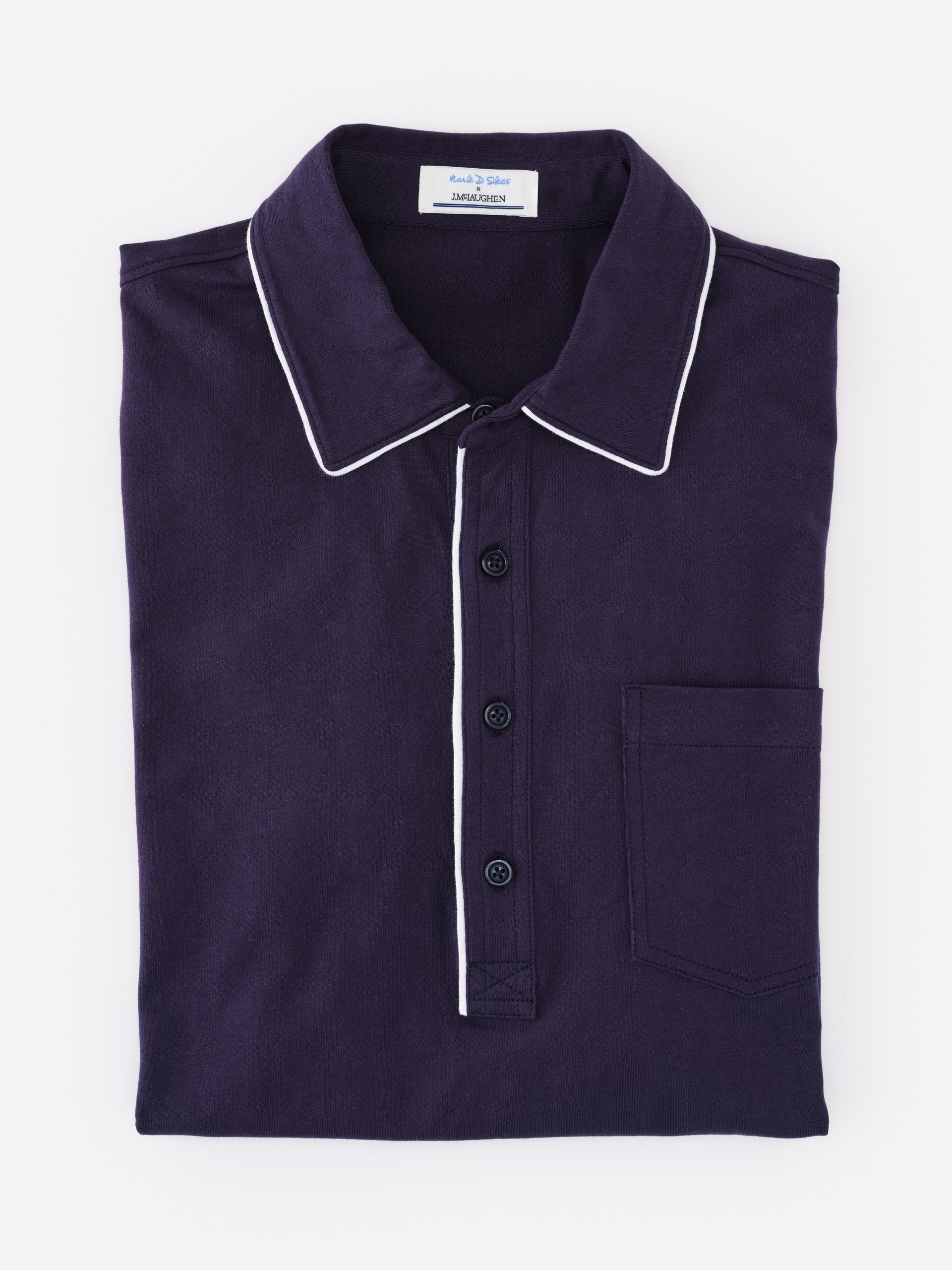Folded navy blue Ryan Polo shirt by J.McLaughlin featuring white trim on the collar and button placket, showcasing effortlessly stylish, enduring designs and innovative fabrics.