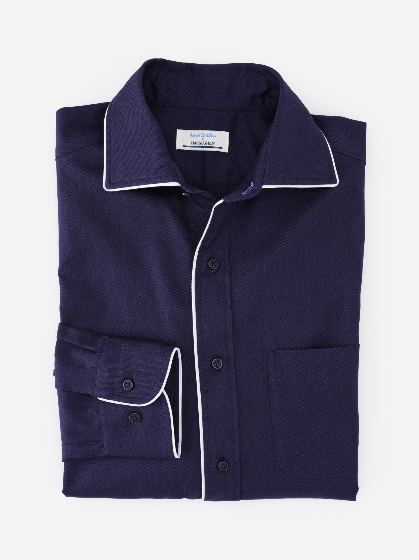Folded Anderson Cotton Shirt by J.McLaughlin in deep navy with white piping accents on collar and cuffs, showcasing effortlessly stylish, enduring designs and innovative fabrics.