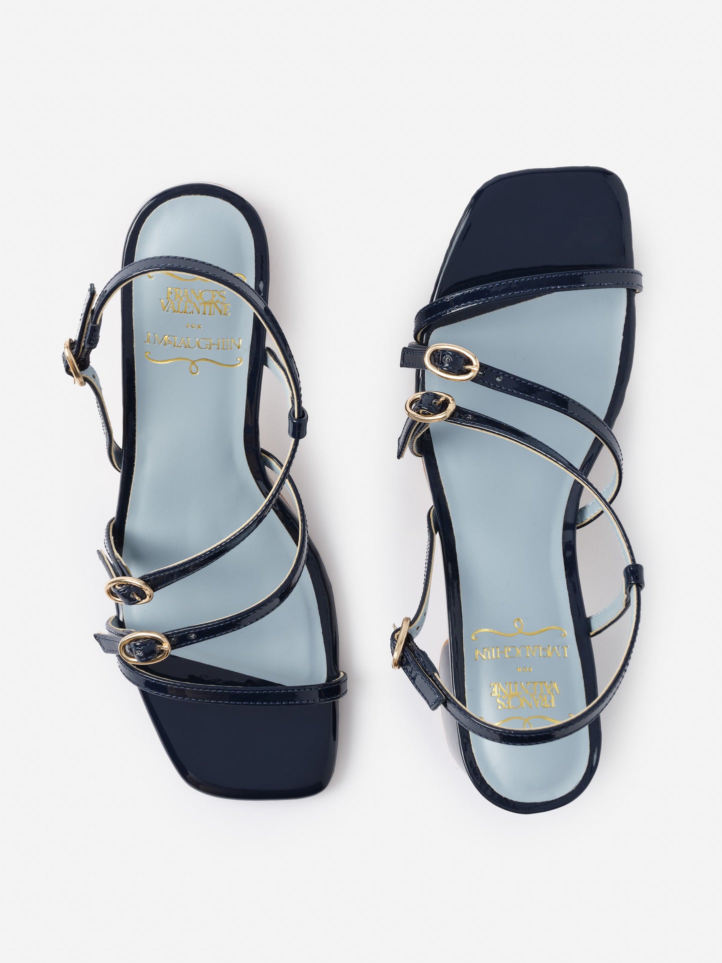 Lexi Heels by J.McLaughlin feature sleek navy straps with gold-tone buckles on a light blue footbed, blending effortlessly stylish design with enduring craftsmanship for timeless fashion.