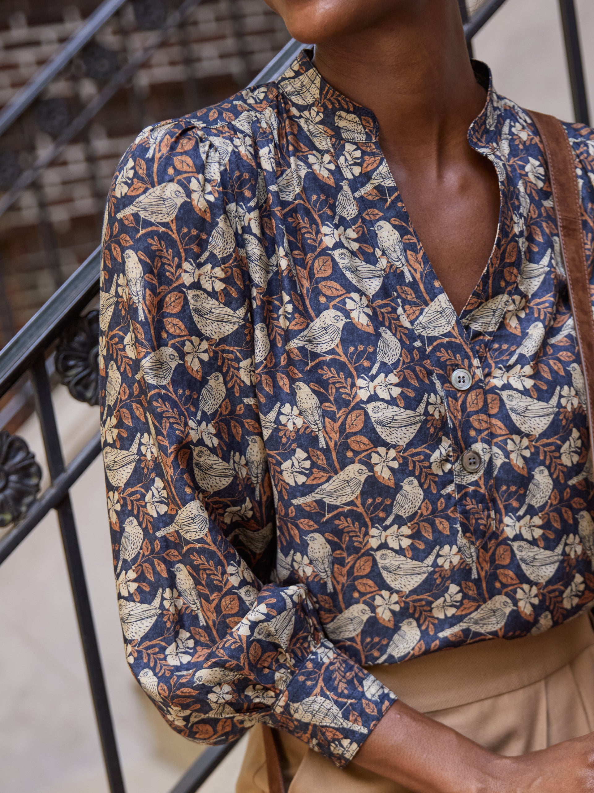 Model wearing J.McLaughlin Rashell blouse in charcoal/camel made with viscose/silk.