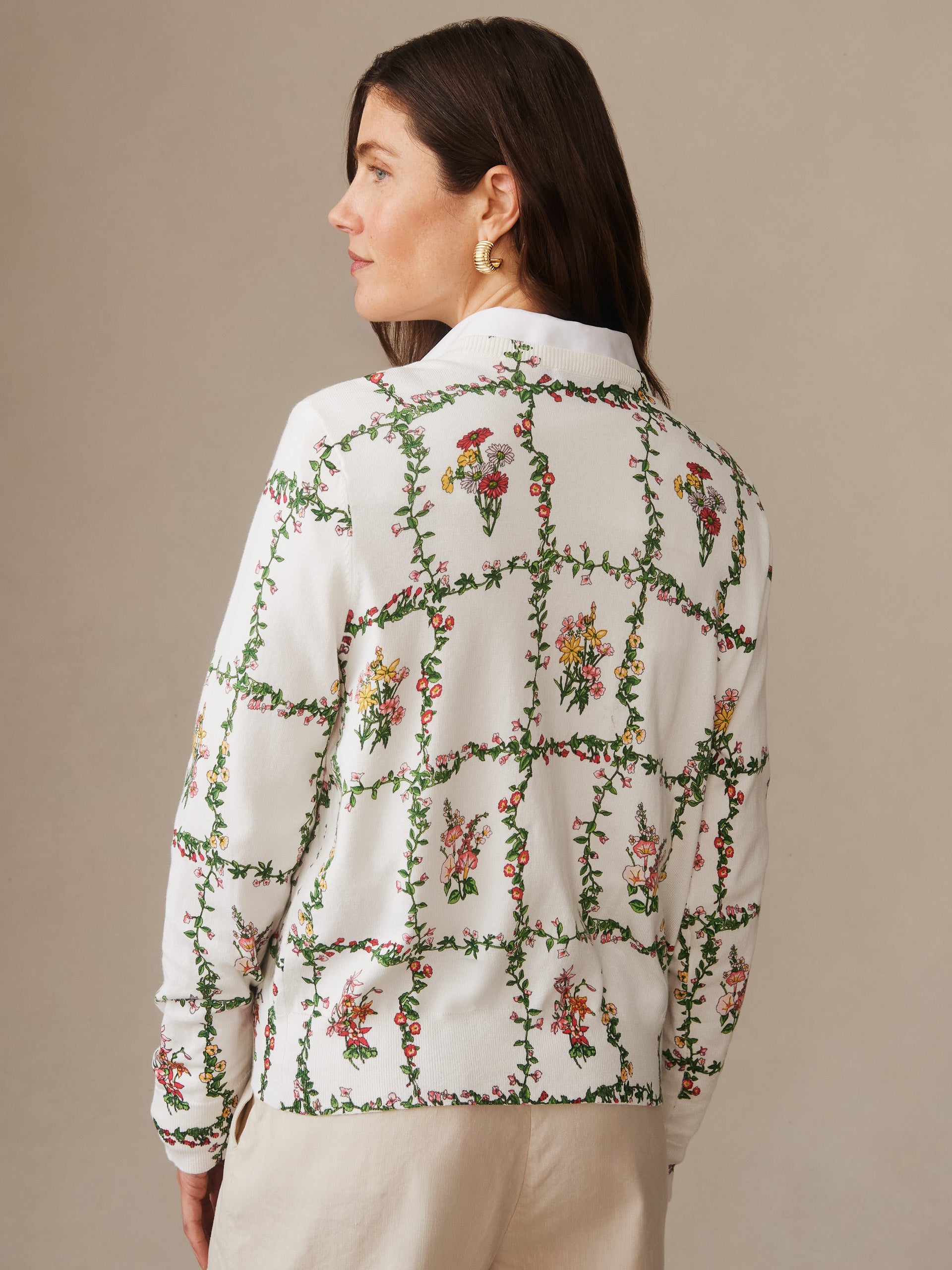 Woman wearing a Whitney Cardigan in Floral Medley Frame by J.McLaughlin, featuring a delicate floral vine pattern on an off-white background, showcasing effortlessly stylish and enduring design.