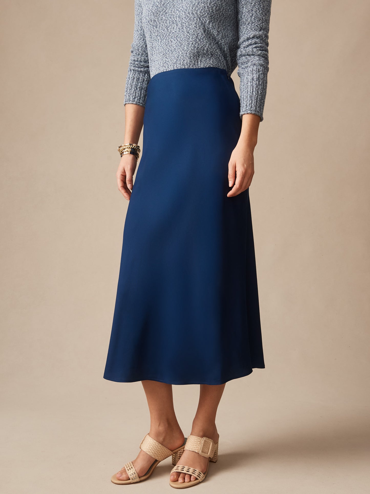 A model wearing a navy Adelyn Skirt by J.McLaughlin paired with a textured gray sweater and beige sandals, showcasing effortlessly stylish, enduring designs with a legacy of timeless fashion. A destination for defining style. Life, Well-Lived.