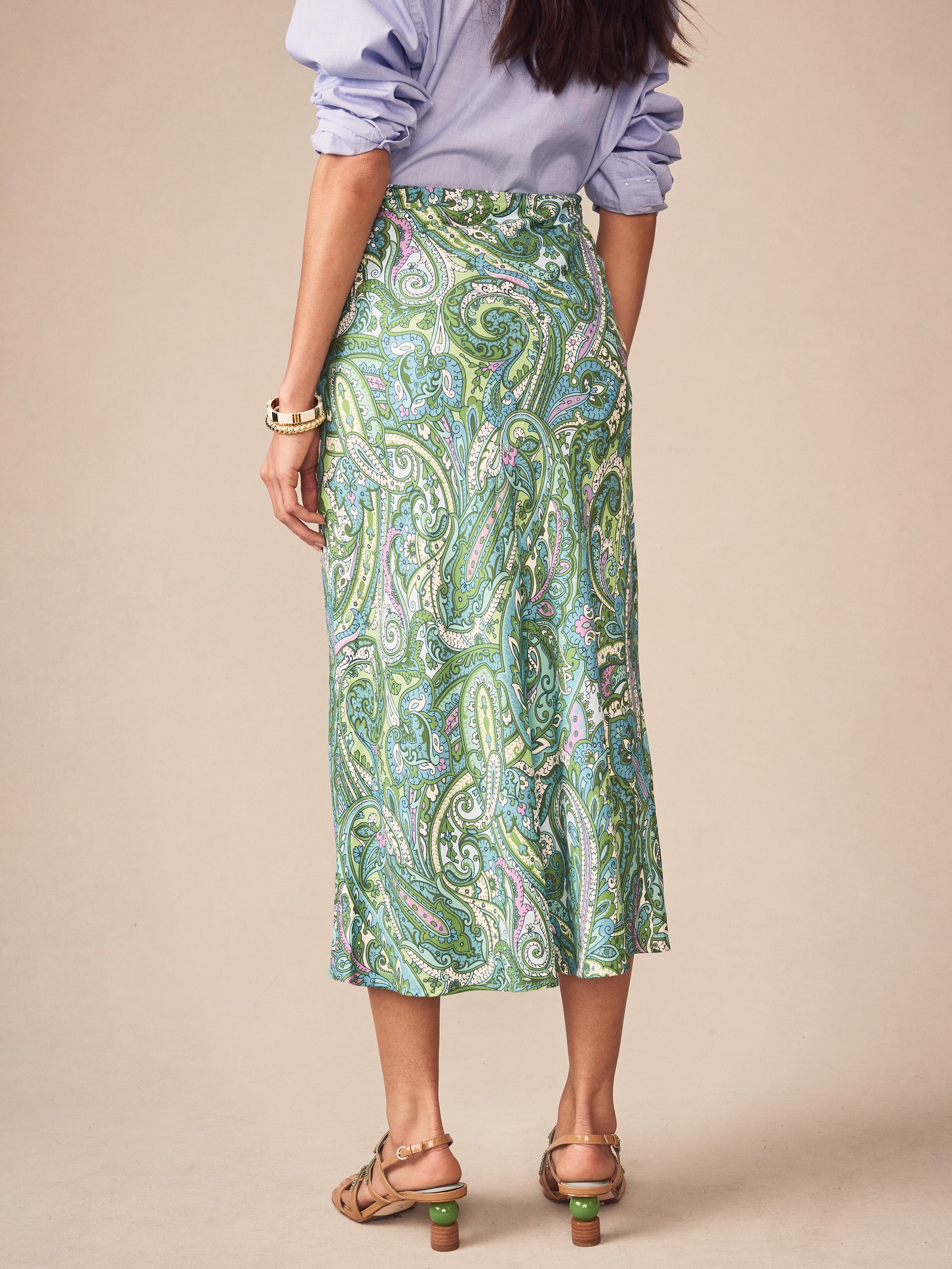Woman wearing the Adelyn Skirt in Paisley Reverie Bias by J.McLaughlin, featuring an effortlessly stylish paisley pattern in green and blue, embodying enduring designs and timeless fashion.