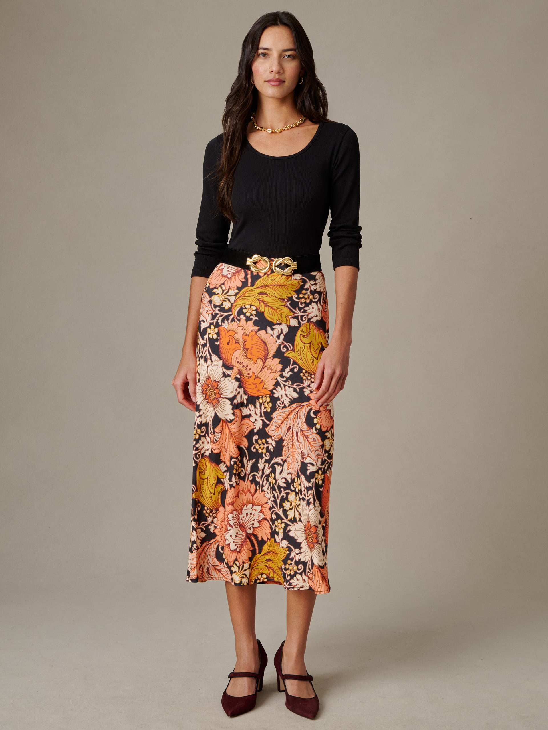 Woman wearing a black long-sleeve top paired with the Adelyn Silk Blend Skirt in City Garden Bias by J.McLaughlin, featuring a vibrant floral pattern and a midi length.