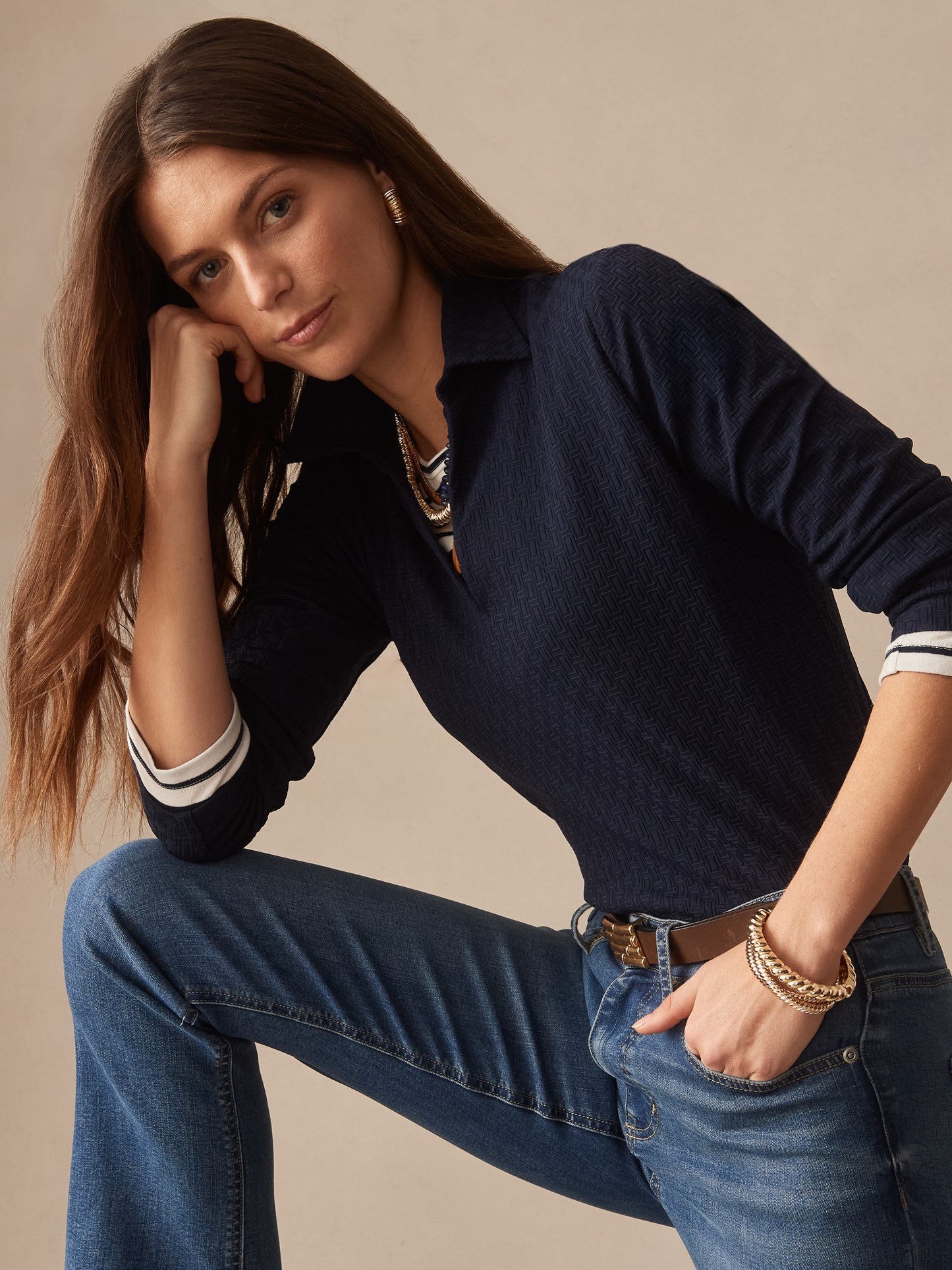 Woman wearing a navy Aida 3/4 Sleeve Top in Dashing Jacquard by J.McLaughlin, paired with jeans and gold jewelry, showcasing effortlessly stylish, enduring designs.