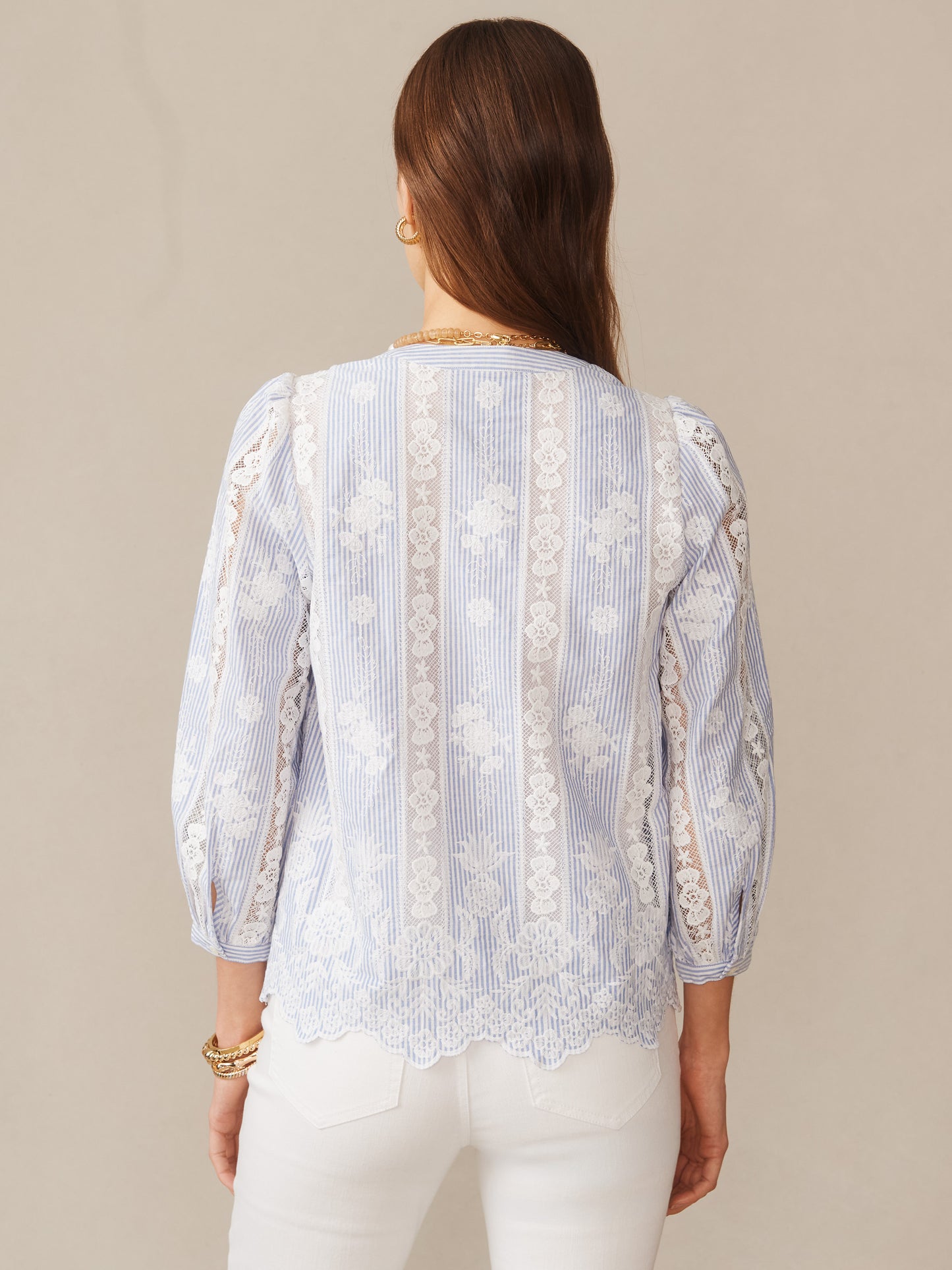 Woman wearing a blue and white Alice Blouse in Stripe by J.McLaughlin, featuring delicate lace details and stripes, showcasing effortlessly stylish, enduring designs.