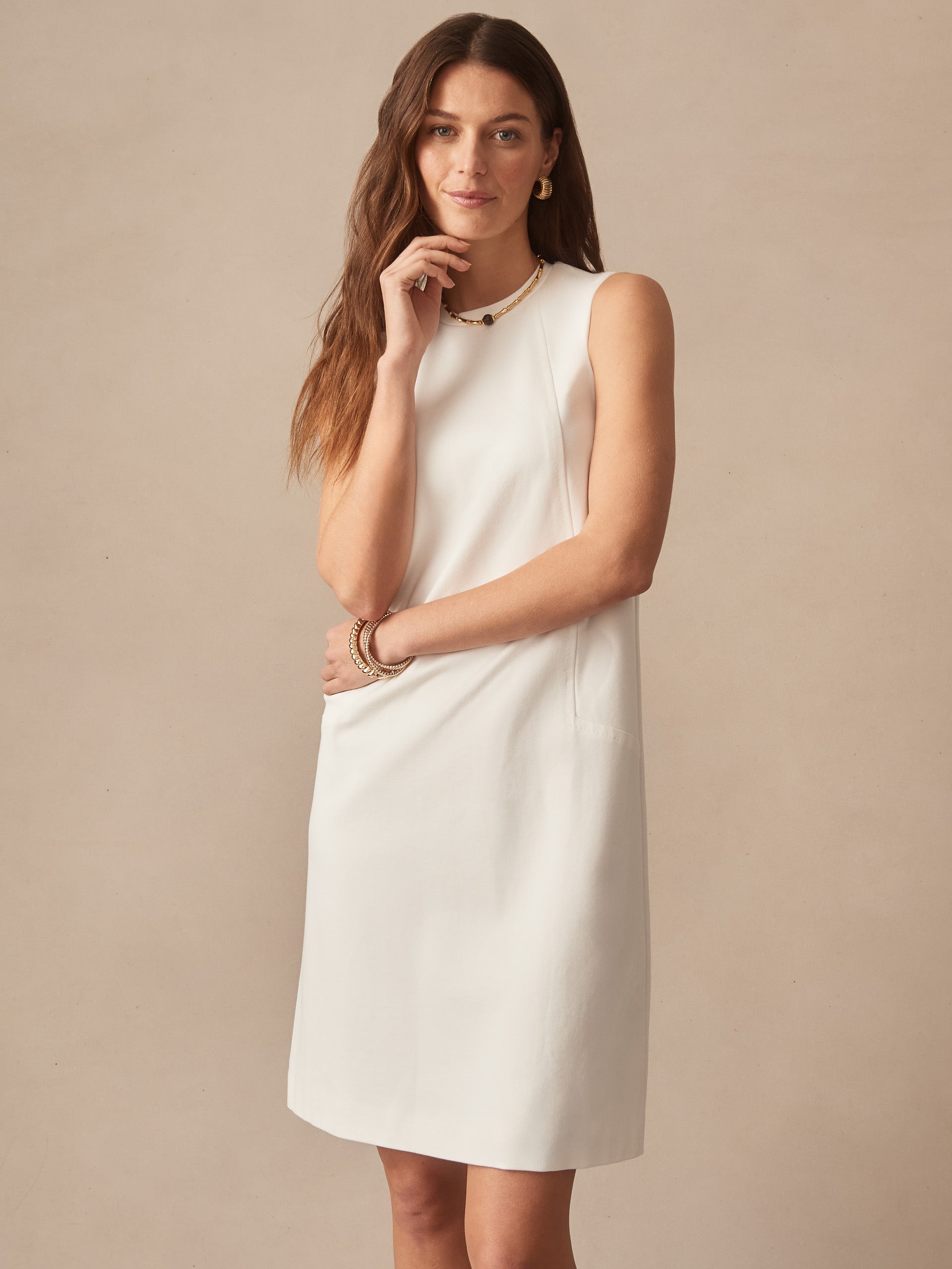 Woman wearing an ivory Alicia Dress by J.McLaughlin, showcasing effortlessly stylish and enduring designs with a classic sleeveless silhouette, perfect for a destination for defining style. Life, Well-Lived.
