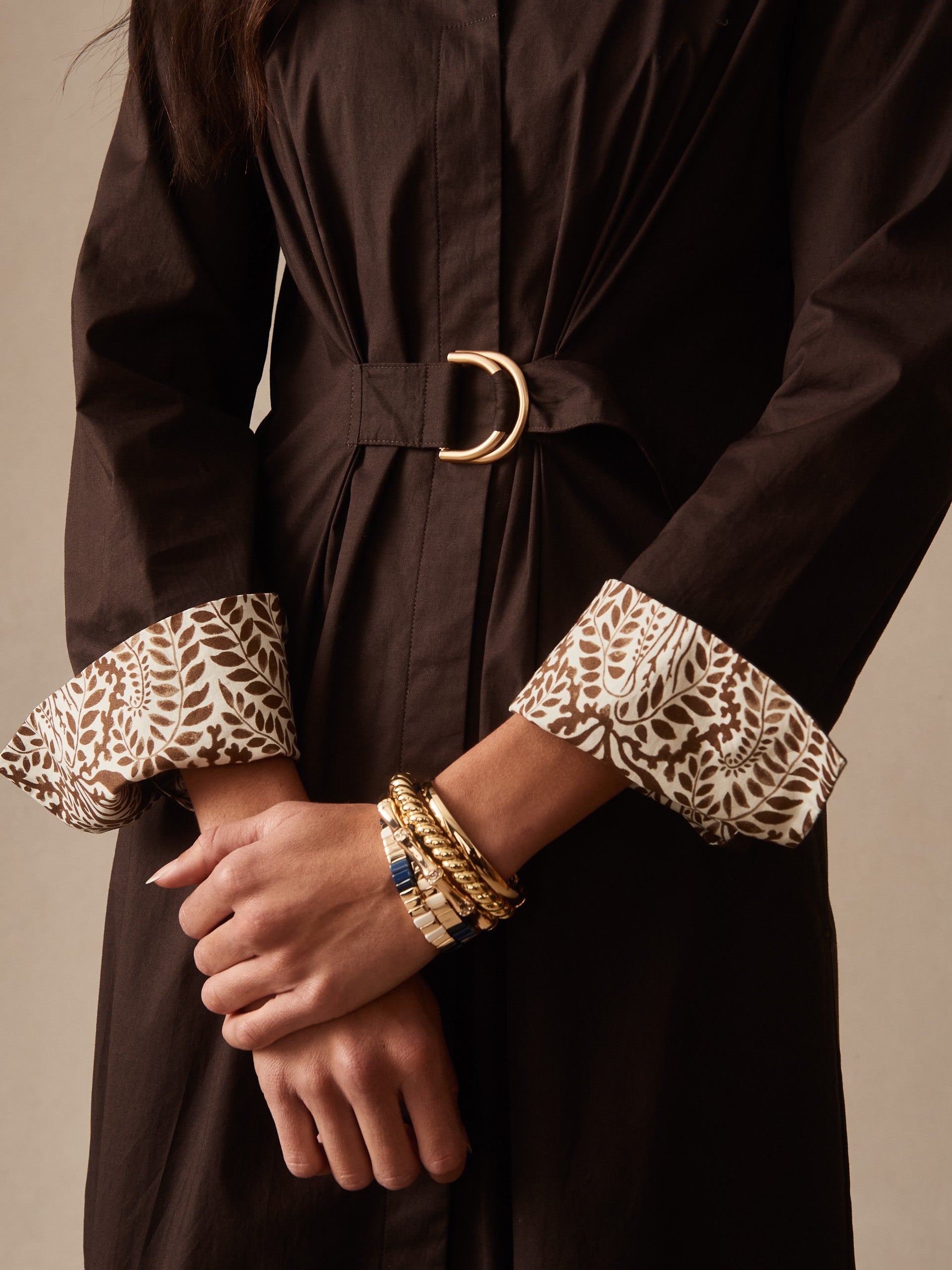 Close-up of a model wearing the Alina Dress by J.McLaughlin in rich chocolate with patterned cuffs and a gold buckle belt, showcasing effortlessly stylish, enduring designs and innovative fabrics.
