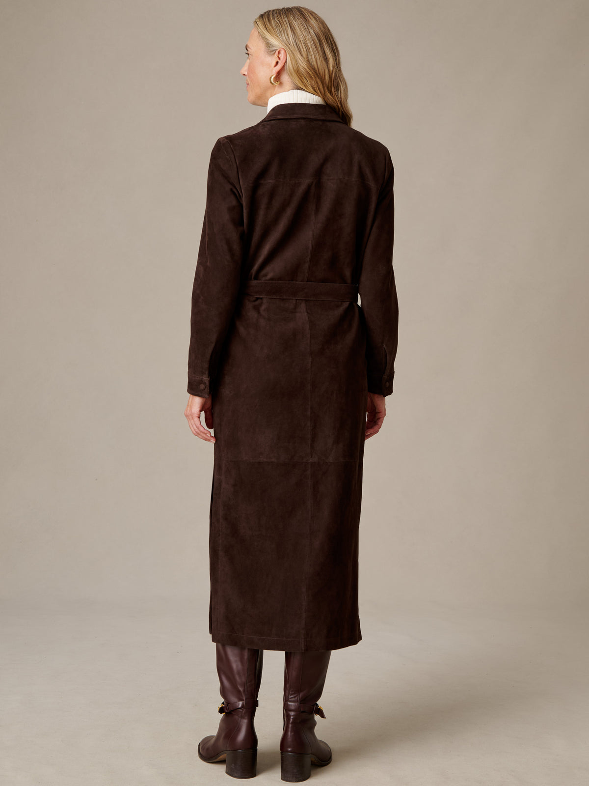 Back view of a woman wearing the J.McLaughlin Amory Suede Maxi Dress in rich chocolate brown suede with long sleeves and a defined waist styled with brown boots