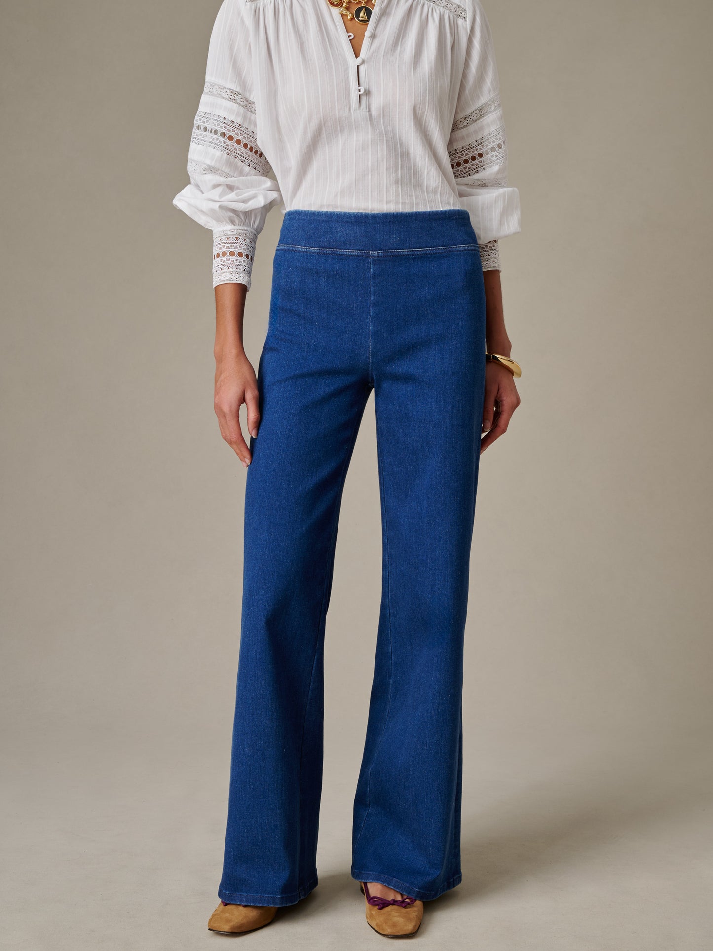 Woman wearing Anderson Jeans by J.McLaughlin in a timeless classic style, paired with a white detailed blouse and neutral shoes, showcasing enduring design and quality craftsmanship.