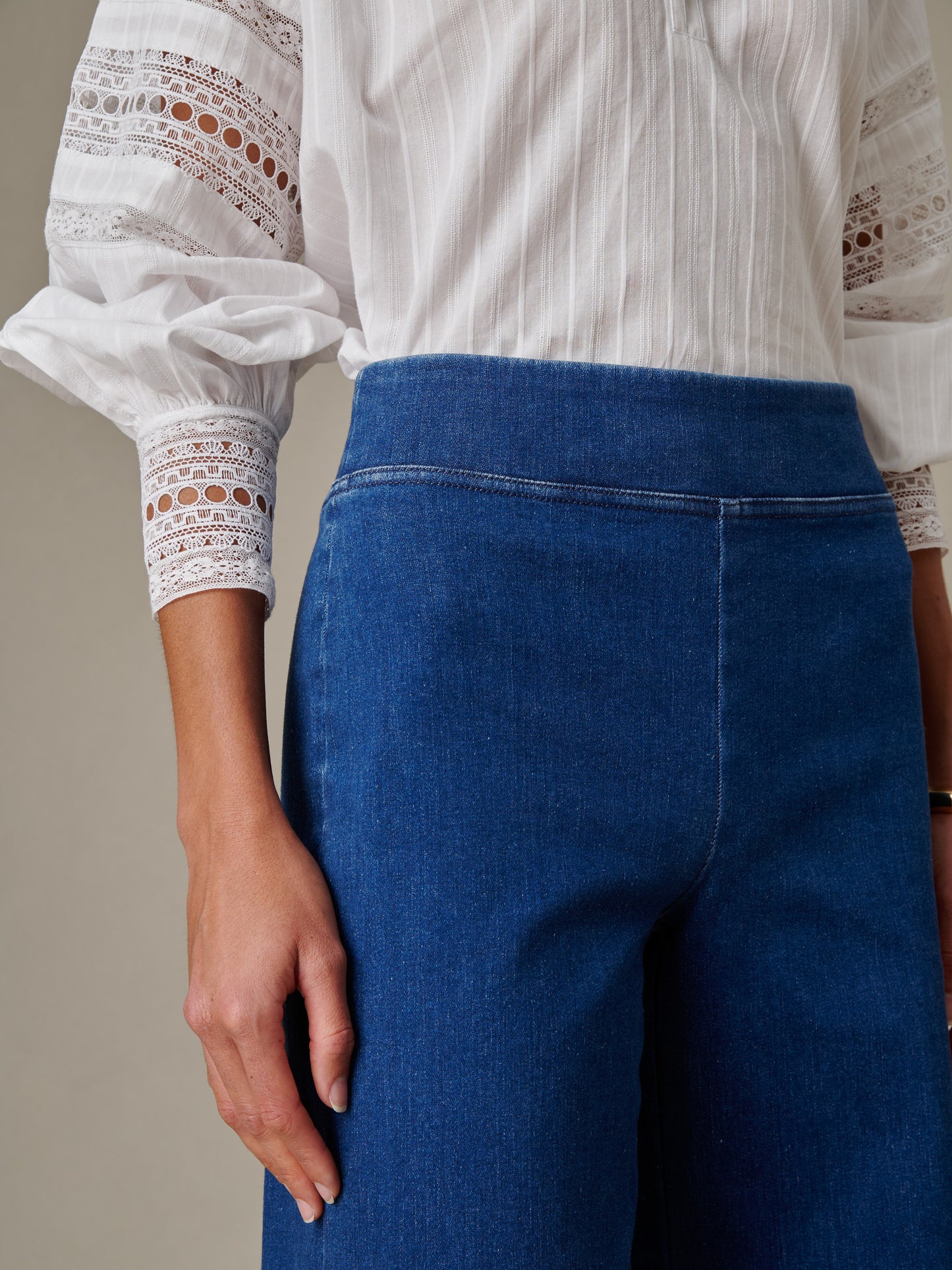 Close-up of a person wearing Anderson Jeans by J.McLaughlin, showcasing effortlessly stylish, enduring designs paired with a classic white blouse with lace details.