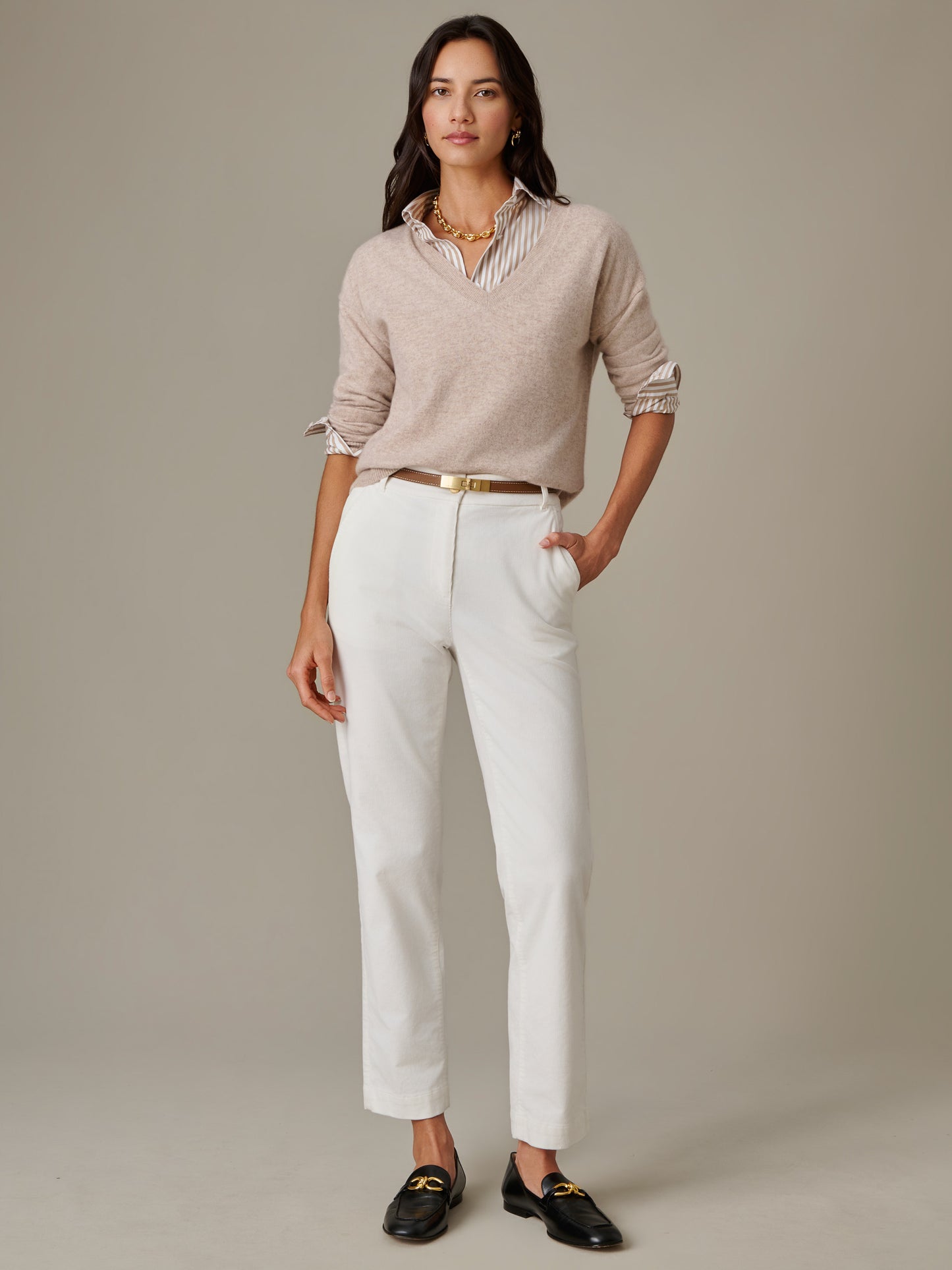 A woman wearing Avery Corduroy Pants styled with a beige sweater over a striped blouse, accessorized with a gold belt and black loafers, showcasing J.McLaughlin's timeless, effortlessly stylish look.
