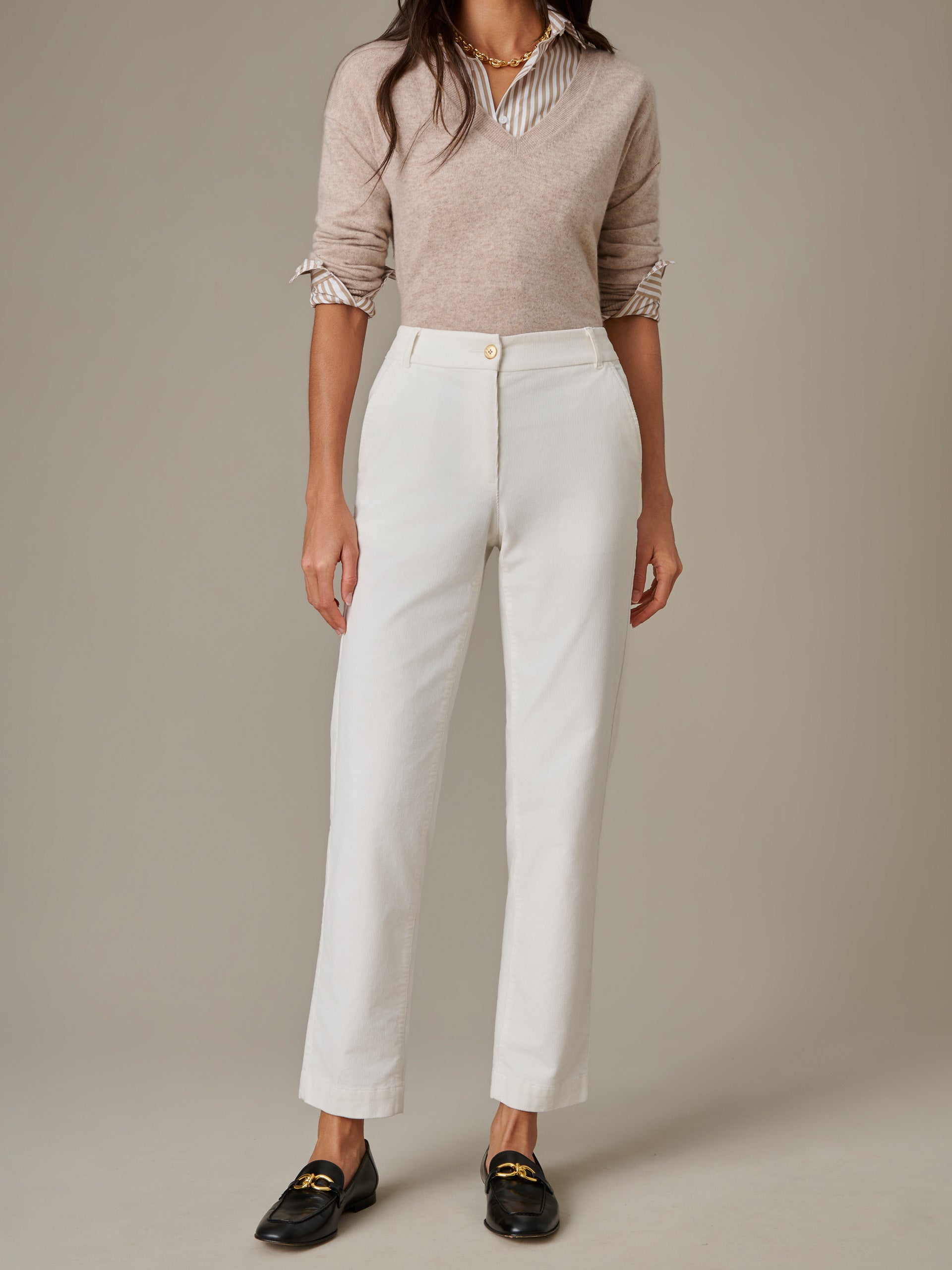 Woman wearing beige sweater and striped blouse paired with white Avery Corduroy Pants by J.McLaughlin, styled with black loafers and gold necklace for an effortlessly stylish look.